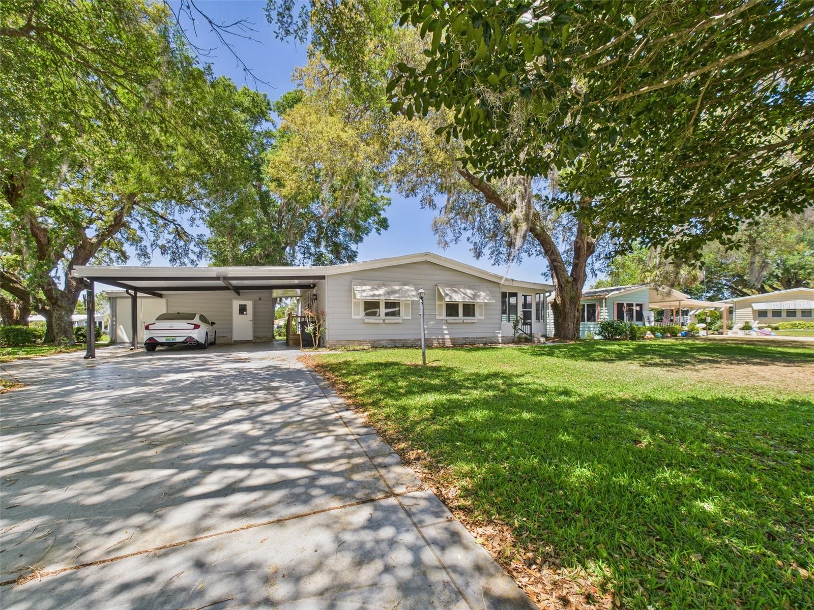2/2 Manufactured Home Located in The Villages! This Home is in a Cul-De-Sac on a large corner lot with Majestic Oaks and Mature Landscaping to enjoy the great Florida weather. There is also an Enclosed Lanai with separate entrance for extra living space. The 2 space carport has a golf cart garage/workshop/laundry room for your convenience. Insulated windows were installed in 2014 and A/C in 2017. The versatile 2nd Bedroom has a Murphy Bed for guests or can be used as an office or craft room. Spanish Springs Square, as well as shopping, dining, recreation and medical facilities are minutes away and accesabile by golf cart. Come enjoy all that The Villages has to offer with this home!