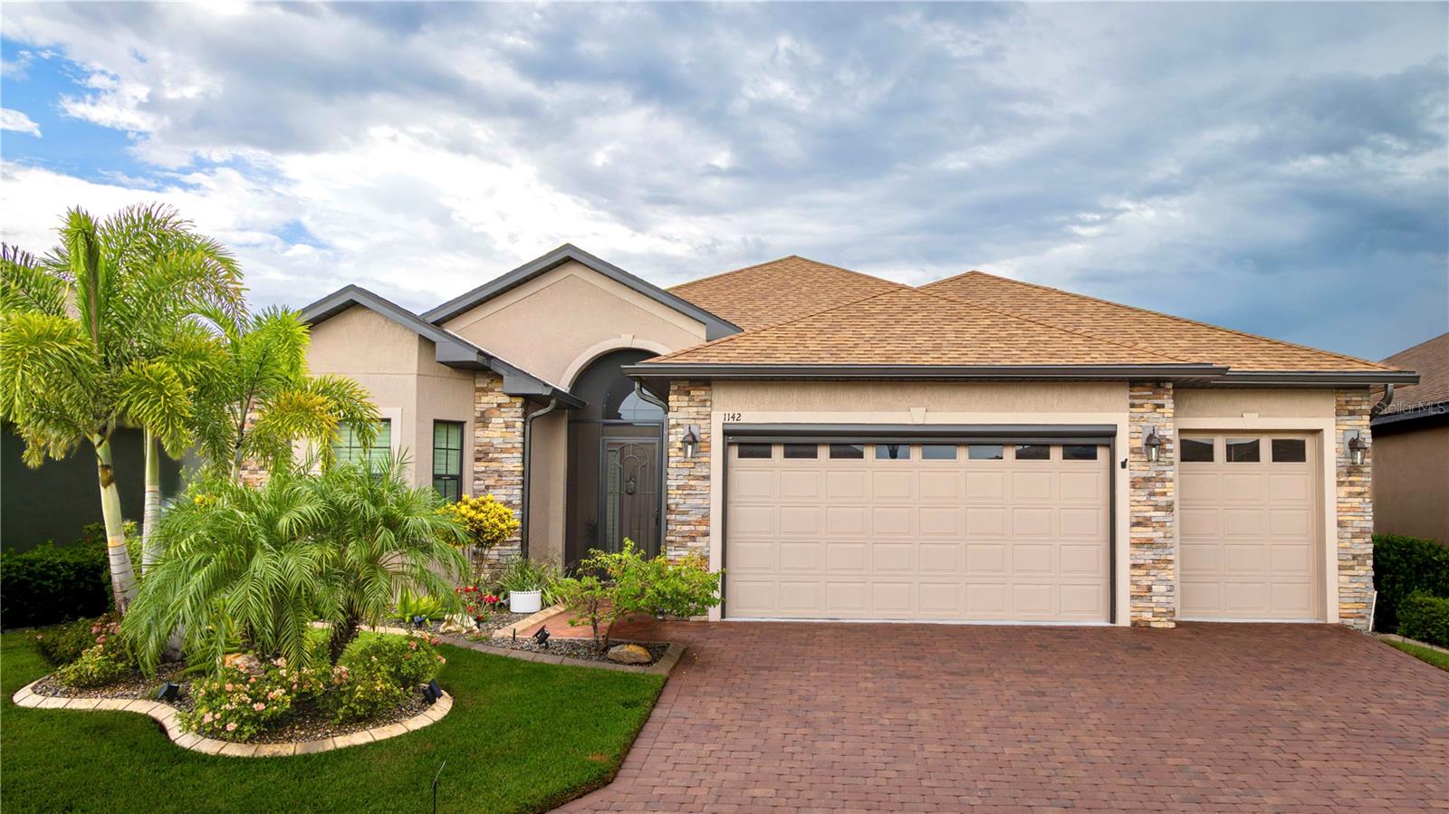 Welcome to your next chapter in beautiful Lake Ashton—Central Florida’s premier 55+ active-adult community. This immaculate, nearly new home (just 3 years young) offers a perfect blend of tasteful style, elegance, and Florida charm. With 3 spacious bedrooms and 2 full baths, this open-concept floor plan, with 10’ ceilings and 8’ doors, feels spacious, yet warm and comfortable. It is ideal for both relaxed living and gracious entertaining. Upon approaching the home, you will immediately be impressed by the exterior stone facing, beautiful landscaping with concrete curbing and small river rock, the full-width paver driveway, bronze trim and gutters, and front screened entry. The spacious living area is highlighted by an amazing chef’s kitchen with stunning white cabinets, and a one-level island providing additional kitchen workspace. The kitchen alone features over $30,000 in upgrades, including the outstanding chef’s KitchenAid stainless steel appliance package with PrintShield Finish, a 36” induction cooktop and separate, built-in oven and microwave. The base kitchen cabinets were extended to the west exterior wall. The kitchen and flex room feature abundant cabinets, shelving, and storage areas. The living room and primary bedroom have elegant coffered ceilings, and the primary bedroom has a spacious, custom walk-in closet. The home is accented by custom tile flooring throughout. The sliding glass doors are pocketed to allow fully opening to the expanded, screened veranda. With its panoramic view overlooking the golf course, the veranda is splendid for both entertaining and relaxing in your delightful residence. The home features custom fans, hardware, and lighting throughout, as well as five pocket doors. In total, the home has over $198,000 of custom upgrades, making it truly a signature residence! More than a neighborhood, Lake Ashton is a lifestyle. Residents enjoy two 18-hole championship golf courses, a 26,000 sq ft clubhouse, a state-of-the-art Health & Fitness Center, both indoor and outdoor swimming pools, pickleball courts, bowling alley, theater, on-site restaurant, and a vibrant calendar of social events and clubs. Don’t miss this exceptional opportunity to own a home that truly has it all. Call today to schedule your private showing—your Florida dream awaits!