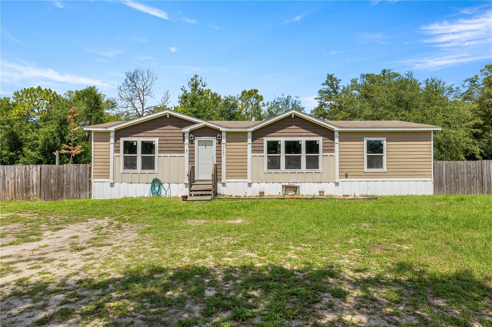 Move-in ready and full of charm, this 2018 doublewide manufactured home offers space, comfort, and privacy—all situated on a desirable corner lot at the end of a quiet road. The 3-bedroom, 2-bath split floor plan features a spacious primary suite complete with a large walk-in closet, dual vanities, a soaking tub, and an oversized walk-in shower. The heart of the home is an open-concept living area filled with natural light and accented by crown molding and thoughtful design touches. The living room includes a built-in entertainment space, while the kitchen boasts ample cabinetry, counter space, and a layout ideal for everyday living or entertaining. Step outside to enjoy the fenced backyard and back deck—perfect for relaxing, pets, or outdoor gatherings. With no rear neighbors and extra privacy from the dead-end street location, this home offers the peaceful lifestyle you've been looking for.