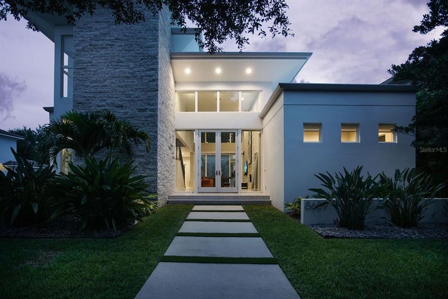 Located within the gates of Lake Nona Golf & Country Club. This stunning modern-transitional home was designed and built by award-winning custom home builder Phil Kean Designs. The two-story floor plan redefines modern Lake Nona living with its minimalist architecture and stylish interior centered on an indoor-outdoor lifestyle.  The interior of the four-bedroom home brings a refreshing blend of contemporary design, comfort and pure luxury.  Dramatic ceilings and stacked-stone feature walls create a modern aesthetic, and an open staircase serves as a focal point throughout the primary living area, which includes the great room, contemporary kitchen and formal dining room.  The minimalist kitchen offers a gorgeous aesthetic with functional shelving, bar seating, solid white countertops and sleek wooden cabinetry.  The owner’s suite overlooks the courtyard pool and offers a wooden accent wall and multiple sliding glass doors that flood the room with plenty of natural light.  Neutral tones in the owner’s bath create a relaxing haven from which to enjoy the glass walk-in shower, soaking tub and large vanity with dual sinks.  Designed for indoor-outdoor living, floor-to-ceiling glass sliding doors open from the great room, breakfast nook and owner’s suite to reveal an open-air pool, spa and covered lanai with fireplace, summer kitchen and motorized retractable screens.  Additional features include a first-floor laundry room, an office / flexible fourth bedroom and a two-car garage with golf cart storage.