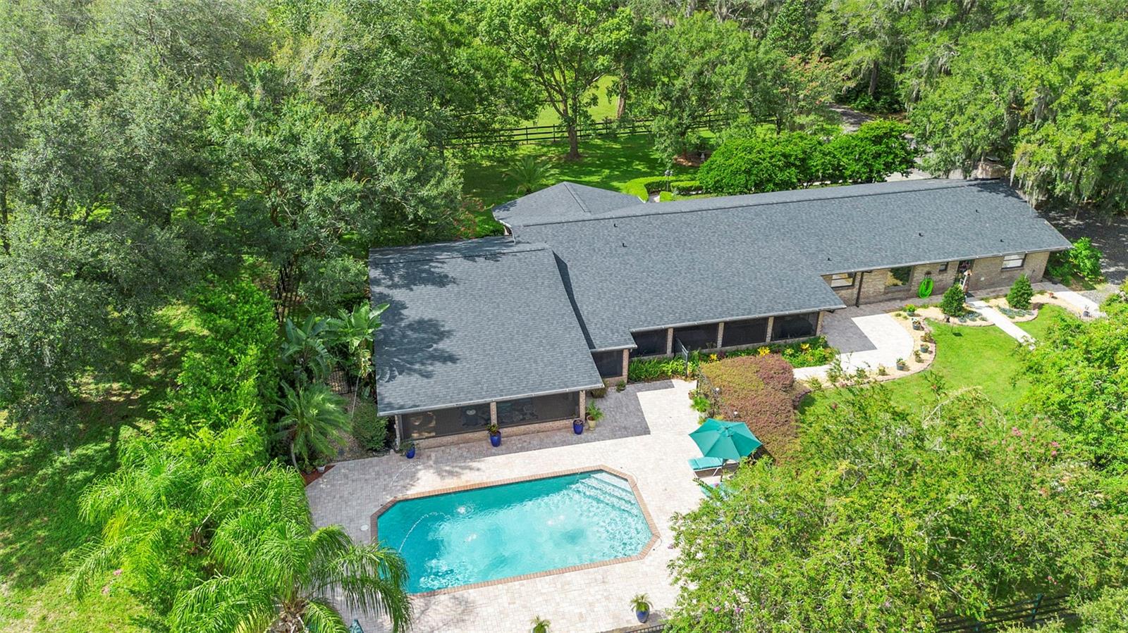 A Private Retreat – This custom-built estate in sought-after Glenwood DeLand offers a welcome blend of privacy, flexibility, and the true Florida lifestyle. What the owners love most is the location, the exceptional privacy, and the views from nearly every space in the home. The front porch is a favorite spot, offering a beautiful vantage point over the property, while the lower lying pasture is both scenic and unusually well-suited for use.
Past the gated entry and a tree lined driveway, the home welcomes you with an open plan designed for both comfort and connection to nature. Four bedrooms plus a large office (or 5th bedroom/bonus room) three and a half baths, and two elegant master suites—each with direct access to the lanai—provide ideal spaces for generous, even multigenerational living. The fully equipped kitchen features floor-to-ceiling custom cabinetry with pull-outs, while a separate butler’s pantry—located near the wet bar and powder room—adds its own refrigerator, dishwasher, and sink for effortless entertaining. The private views to the estate's meadows are available from anywhere in the home.
Outdoors, the resort-style pool area is the heart of the property, complete with a stone fireplace, fountain feature is located in front of an expansive screened enclosure. The versatile two-story detached garage and workshop accommodates five cars on the upper level, while the lower level offers stalls and a tack room—perfect for horses, hobbies, or additional storage.
Recent upgrades include a new roof, dual AC units, garage insulation and electrical, RainBird irrigation, and a newly paved driveway. With cross-fencing, easy-care landscaping, and a location just minutes from Downtown DeLand, the beaches, and area attractions, this is a private sanctuary perfectly placed for both seclusion and convenience. A recent appraisal is on file, underscoring the excellent value offered by this exceptional property.
