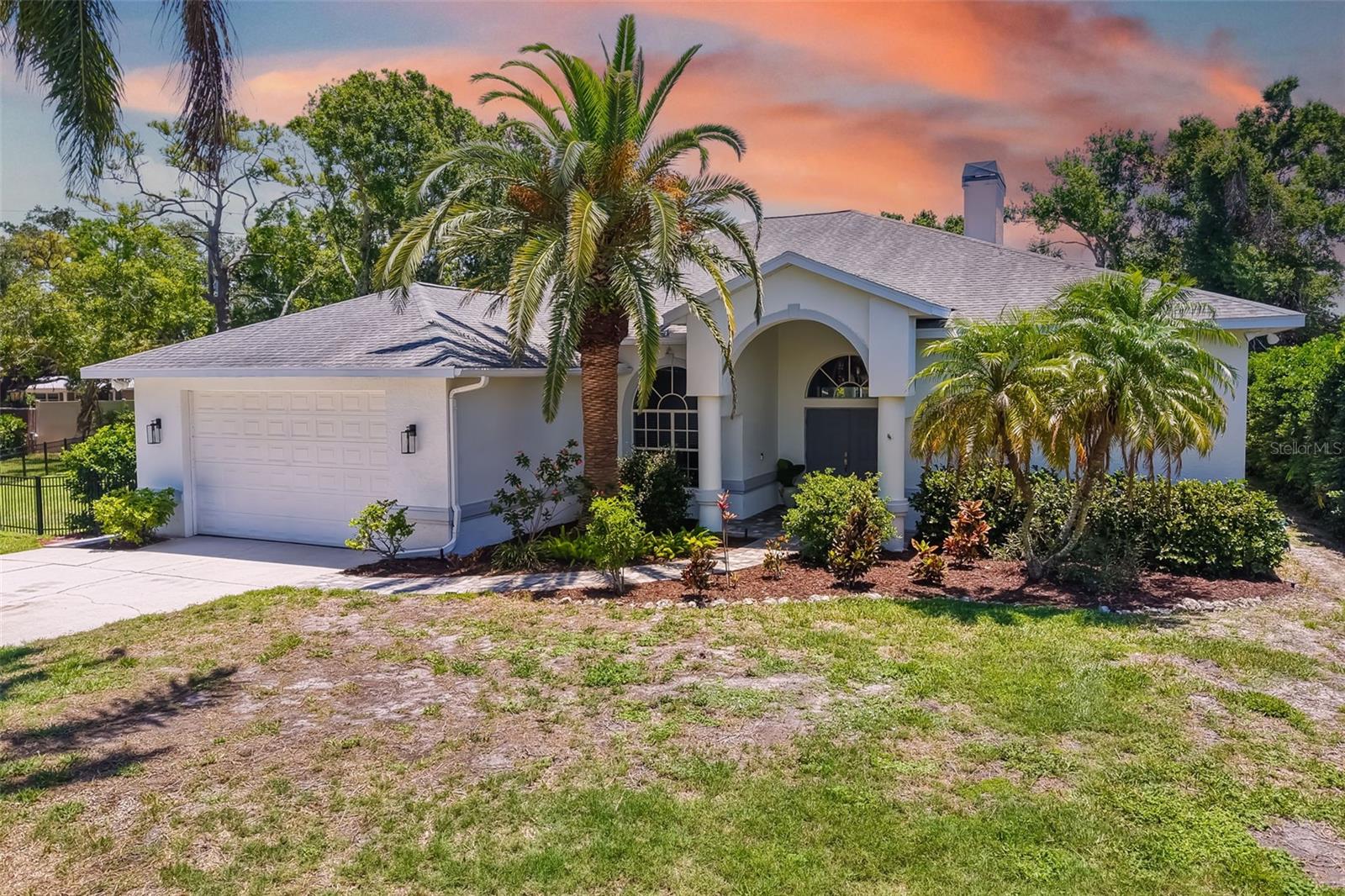 Welcome to Oak Ridge, a charming enclave of custom-designed homes. This well-maintained 3-bedroom pool home sits on an oversized, desirable lot. A grand covered entry with double doors opens from the paver walkway into a bright and inviting interior, featuring soaring 12-ft ceilings, enhanced crown molding, and 20-inch porcelain tile laid on the diagonal throughout the main living areas and tile plank flooring in the bedrooms. Light, neutral tones create a fresh and airy atmosphere. The spacious living room offers a gas fireplace accented with Key West coral and large sliding doors that open to a covered and screened lanai, offering seamless indoor-outdoor living. The recently renovated kitchen is complete with new cabinetry, updated plumbing, stainless steel appliances, subway tile backsplash, and a cozy dining nook overlooking the sparkling heated pool. Just off the kitchen, a comfortable family room offers a second fireplace, currently used as wood burning but connected to gas, providing both character and flexibility. The split-bedroom floorplan ensures privacy, with the luxurious primary suite serving as a true retreat. A sitting area, gas fireplace, lanai access, large walk-in closet and a wet bar with refrigerator enhances the convenience, making this a perfect owner’s getaway. The ensuite bath features dual vanities, granite countertops, expansive walk-in shower, soaking tub and private water closet. Two additional bedrooms and a full bathroom are located on the opposite side of the home for optimal privacy. The interior laundry room offers excellent storage with a large closet and extensive shelving, along with a built-in security system. Outdoor living is resort-style, centered around an expansive screened lanai that includes a beautifully finished outdoor living room with porcelain plank tile and a decorative wood ceiling overlooking the heated pool. The custom-designed outdoor kitchen is complete with a gas grill connected to a 250-gallon submerged propane tank, full-size refrigerator, and ample counter and storage space. Precast stone balustrade railings define the outdoor entertaining areas, which include an additional patio and generous yard space ideal for kids and pets. Additional highlights: replaced roof (2017), water heater (2021), gas pool heater (2021), pool pump (2024), recently serviced outdoor grill, 3-ft black rod iron fencing, reinforced vinyl fencing, updated lighting and fans, 3 gas fireplaces, hardwired speaker system throughout, exterior security cameras, recessed lighting, central vacuum, and an oversized 2-car garage with built-in shelving for maximum storage and a high-clearance garage door suitable for taller vehicles. Surrounded by mature landscaping that provides privacy and tranquility, this home is ideally located just minutes from the award-winning white sands of Siesta Key Beach, the Legacy Trail for biking and walking, multiple healthcare systems, and a vibrant array of shopping, dining, and cultural attractions.