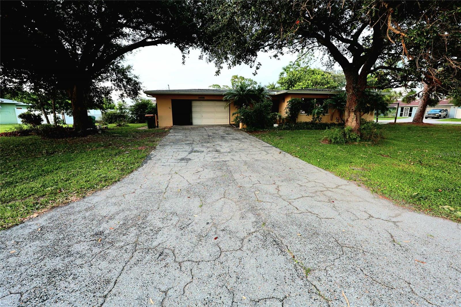 Charming 2 Bedroom, 2 Bath Home on a Spacious Corner Lot in Port Charlotte
Welcome to this 2 bedroom, 2 bathroom home offering over 1,600 square feet of living space, perfectly situated on a large corner lot in the desirable New York section of Port Charlotte. Full of potential, this property is ready for someone to bring their personal touch and a little love to make it truly shine.
Enjoy the natural beauty of mature oak trees that provide both shade and charm. The fenced backyard offers privacy and plenty of room for outdoor living, pets, or gardening. A spacious lanai with vinyl screen windows creates a comfortable space to relax or entertain in any season. Inside, you'll find an inviting layout with a large family room that could easily be converted into a third bedroom, offering flexibility for growing families or guests. The home also includes an inside laundry room, an attached two-car garage, and a separate workshop area—ideal for hobbies or extra storage. A new roof was installed in 2023, providing peace of mind for years to come.
Centrally located, you’re just minutes from shopping, dining, schools, and everything Port Charlotte has to offer. Whether you're a first-time homebuyer, seasonal resident, or investor, this is a wonderful opportunity to own a well-built home with great bones and endless potential.