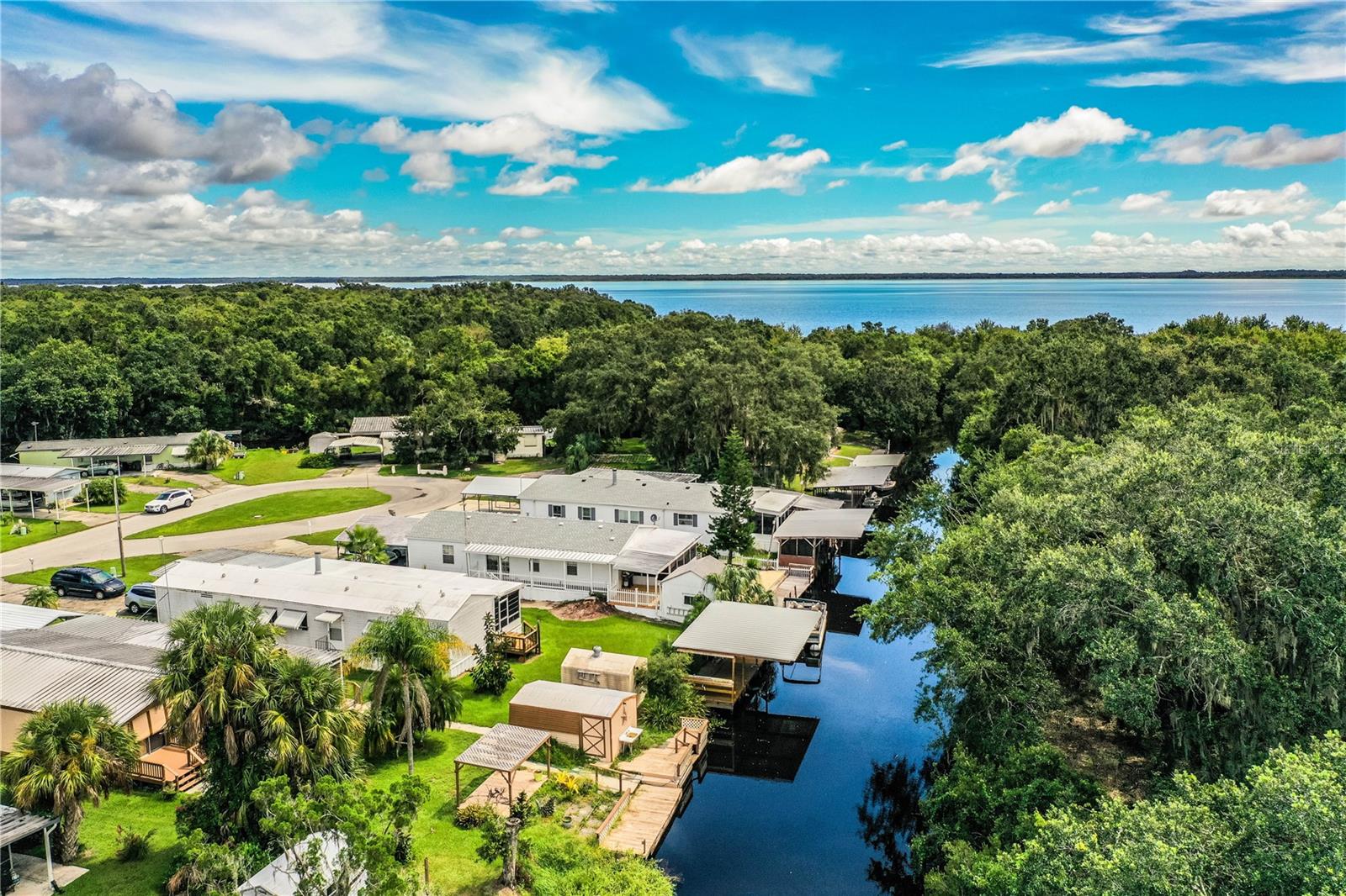 Welcome to Your Fisherman’s Paradise in the waterfront retreat of Rosalie Oaks. Nestled along a peaceful canal with direct access to Lake Rosalie and the stunning Kissimmee Chain of Lakes, this move-in-ready, 2003 Palm Harbor manufactured home offers the ultimate waterfront lifestyle. Located in the serene Rosalie Oaks community, this well-maintained home sits right at the water’s edge and features its own private boat dock that will provide easy access to your water bound vessels. From here, enjoy effortless boating through Tiger Creek to Tiger Lake, the Kissimmee River, and even the Intracoastal Waterway, a true haven for anglers, boaters, and nature lovers alike. Step inside to discover an open, airy floor plan with 1,800 sq/ft of living space, 3 spacious bedrooms, 2 full bathrooms, and a bonus office/nursery off the primary suite. The inviting great room boasts a cozy brick wood-burning fireplace, built-in bookshelves, and plenty of room for your large living room furnishings. The chef-style kitchen is designed for functionality, offering abundant counter space, cabinetry, storage, and both prep and dining areas. Durable laminate and ceramic tile flooring run throughout the main living spaces for easy maintenance. Relax year-round in the 19x9 screened lanai overlooking the tranquil canal or entertain guests on your expansive 48x11 wooden waterfront deck with porch swing, just steps from the dock. A new roof was installed in July 2023, giving added peace of mind. Enjoy the calm of a quiet and peaceful community, just minutes from the renowned Camp Mack Fish Camp, Freshwater Tavern & Grill, and the scenic Kissimmee River State Park — perfect for hiking, birding, and outdoor adventures. Frequent visits from deer and wild turkeys add to the natural charm of this unique retreat. Other great features include a complete appliance package, (including washer and dryer), additional refrigerator, and freezer located in the utility room, rain gutters, 2 outdoor sheds with electricity, covered carports that can accommodate 3 vehicles, public water and sewer, and much more. Whether you're looking for a permanent residence, a winter getaway, or the perfect weekend fishing camp — this property checks all the boxes. This home is easy to view, so schedule your tour today and bring all offers!
