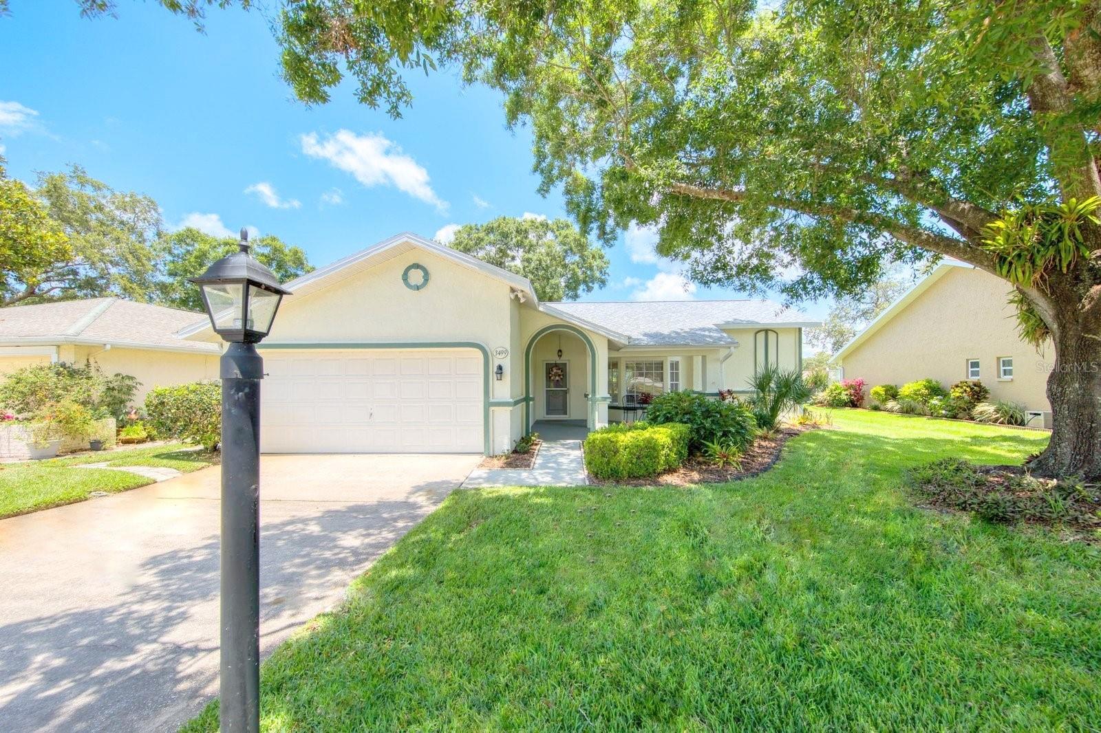 Casual elegance achieved in this golf course view home on one of Highland Lakes' most desirable streets! Situated on the 3rd fairway of the Red Course, you'll enjoy lush green views from inside and out. This is larger open concept split bedroom plan is upgraded with quality materials tastefully coordinated. Perfect for comfortable living & easy entertaining, the central open kitchen features wood cabinets, rich granite counters, efficient prep and serving areas, and a new feature: a beverage center with separate refrigeration for frosty chilled beverages & perfectly cooled wines. This kitchen makes the most of the view too with a bay window dining area adjoining the comfortable family room with a large view window and an electric fireplace. Updated & matching tile flooring throughout all open spaces & wet rooms. Easy care coordinating luxury vinyl planks in a driftwood shade grace both bedrooms. The spacious & serene master suite is big enough for king-size furnishings and offers a well-outfitted walk in closet, & new ensuite with two shower heads. Sliding doors from the master offer a view, natural light, and open to the lanai. The large newly screened lanai with matching tile flooring & outdoor-rated ceiling fans spans from the MBR all the way to the kitchen sliders. A new paver patio provides seating with a view and room for a grill. Bedroom 2 also has a walk-in closet and is across from the hall bath. The laundry room has a utility sink, extra cabinet storage, and access to the oversize garage. It gets better: the roof is 4 years new, HVAC is just 8 years, new water heater, dishwasher, microwave & beverage chiller, there are new stainless gutter guards, new interior paint, and the irrigation system is fed by a cost-saving well. You will love the friendly country club atmosphere in Highland Lakes. It offers more for less than any other Tampa Bay 55+ neighborhood and is in the best possible location! Amenities include free golf on 3 private executive courses and free RV or boat storage. There are tennis and pickleball leagues and they offer beginner clinics. There is a club for virtually every interest or hobby and lots of games groups. The main clubhouse & Lake Lodge are the venues for many entertainment and social events and fitness classes. The Arts and Crafts building has a wood shop, art studios and classes. Enjoy quality of life benefits of living within minutes of world-class Gulf beaches, great restaurants & shopping, exciting pro sports, rich cultural resources, two international airports, and highly respected medical services in a near-perfect climate safely above the flood plain in a non-evacuation zone. The best of Florida's lifestyle is waiting for you!