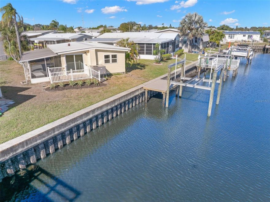 One or more photo(s) has been virtually staged. Your retirement dream home awaits! This 2 bed/1.5 bath waterfront home was recently remodeled down to the studs resulting in a beautiful waterfront retreat complete with 2025 composite dock and 13,000 pound lift. The features are many: 2025 luxury vinyl waterproof flooring with all new subflooring and vapor barrier to protect the floor; new 2025 kitchen with quartz countertops, wood cabinets, stainless appliances and large island making entertaining a breeze; large full bath with marble countertop, step-in shower and comfort height toilet and washer and dryer in utility closet. Primary bedroom has water views and 2025 half bath; guest bedroom can be office/den and has sliding doors to composite deck and water views. Off the kitchen is a 144 sq. ft screened lanai to enjoy the outdoors. All new designer light fixtures, fans and interior paint. The home also boasts drywalled ceilings and walls throughout with R-13 insulation; new HVAC system with ductwork in the ceiling--no vents in floor; new vinyl siding outside; new double paned low E windows throughout; new electrical panel and new wiring throughout; and new energy efficient on demand tankless water heater and new plumbing throughout. This home is like-new without the new home price! Roof has been inspected and is in good condition. Beautifully landscaped. Just move in and enjoy! Price includes share for the lot and ownership in the co-op. Two pets (dogs or cats) up to 35 pounds are welcomed. Home would make a great full-time home, vacation home or investment property as renting is allowed with 2-month minimum. Home is located in popular Americana Cove, a 55+ waterfront community only minutes to downtown St. Petersburg, two airports and 4th Street shopping and restaurants. Low monthly maintenance fee of $380 includes water/sewer, trash pick up, lawn mowing, 24 hr manned gate, heated pool, fitness center, billiards and so much more! Schedule an appointment today to see this affordable waterfront home in a beautiful 55+ community!
