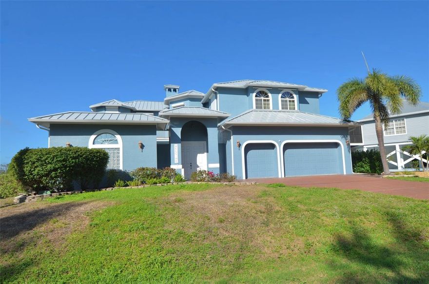 One or more photo(s) has been virtually staged. Discover refined waterfront living in this distinctive 4 bedroom, 3 bathroom residence offering 3,850 square feet of thoughtfully designed interior space along a saltwater canal with access leading toward the Gulf. Blending elevated craftsmanship with meaningful upgrades, the home is anchored by a 2023 metal roof, powered hurricane shutters, and a spacious 3 car garage with overhead storage and built-in shelving. Inside, soaring ceilings create an immediate sense of scale, while elegant architectural arches, recessed lighting, and a polished, cohesive finish add warmth and sophistication throughout the main living spaces. The chef’s kitchen serves as a true centerpiece, appointed with stainless steel appliances, granite countertops, and two oversized islands, one with a sink and butcher-block surface and the other with breakfast-bar seating. Designed for both everyday living and elevated entertaining, the kitchen also features a 6-burner gas range with separate grill and flattop, pot filler, double ovens, a stainless hood, walk-in pantry, and built-in humidor. A striking double-sided fireplace gracefully separates the living and dining areas, creating an inviting backdrop for gatherings and quiet evenings alike. In the living room, a wet bar with utility sink and bar seating adds another layer of convenience, while doors open directly to the private courtyard retreat. Tile flooring enhances the main living areas, complemented by the warmth of wood flooring in the bedrooms. Upstairs, the primary suite offers a tray ceiling, fireplace, a large walk-in closet with built-ins, and two private balconies, one overlooking the water and the other overlooking the pool courtyard. Additional bedrooms feature built-in closets, with the rear bedroom enjoying its own waterfront balcony. Functional details continue with a dedicated laundry room with utility sink and cabinetry, wood stairs with decorative metal railing, and a unique pneumatic tube elevator. Outdoors, the property unfolds into a private resort-style setting. French doors lead to a covered and screened wraparound lanai with ceiling fans and lighting, creating a seamless extension of the home’s living space. The courtyard pool and spa, renovated by Aquatech Pools, are finished with marble pavers and enhanced by a water feature and built-in bench seating, creating a setting that feels both elegant and inviting. For boating enthusiasts, the waterfront infrastructure is exceptional. A composite dock wraps around the 10,000 pound covered boat lift and is accented by solar-powered lighting, making evenings on the water as effortless as they are memorable. Whether heading out for the day or returning at sunset, the dock is designed for smooth daily use. Ideally located near St. Jude Nature Trail, St. James Creek Preserve, marinas, dining, shopping, and everyday conveniences, this residence presents an exceptional opportunity to enjoy a polished waterfront lifestyle with comfort, style, and direct access to the water.