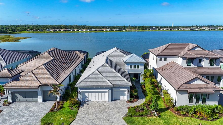 You won't want to miss this one......Indulge in the epitome of lakeside luxury at The Alcove at Waterside by Neal Signature Homes, an exclusive enclave within the vibrant Waterside District of Lakewood Ranch. This stunning residence offers three bedrooms, three full baths, a private den, and 2432 square feet of thoughtfully designed living space with IMPACT RESISTANCE GLASS AND SLIDERS! This beautiful home has a private saltwater pool with LED lights and a large covered lanai area measuring 28 x 17 feet. Plumbed for an outdoor kitchen and comes with electric hurricane screens to give you that peace of mind you are wanting. 
Inspired by a Coastal architecture, the home showcases elegant stucco exterior, a classic tile roof, and refined architectural details. Inside, elevated design touches abound, including custom ceiling treatments, designer wallpaper, and plantation shutters, creating a sophisticated yet relaxed coastal ambiance.
Seamlessly blending indoor and outdoor living, custom 10-foot-high by 12-foot-wide sliding glass doors open to the outdoor living space and frame picturesque views of Blue Heron Lake, filling the home with natural light. Enjoy evening sunsets like you have never seen from your beautiful lanai overlooking the lake.
Additional upgrades include a whole-house Kohler generator for peace of mind, mini-split air-conditioning system in the garage, insulated garage doors, custom ceiling treatments inside and out, automatic sun shade, shell stone pavers that are cool to the touch and additional storage in the garage.
Perfectly located just one mile from the coveted Waterside Place Village, residents enjoy easy access to waterfront dining, boutique shopping, farmers markets, and community events. Center Point at Waterside is only 1.5 miles away, offering even more popular lunch and dinner destinations along with everyday conveniences.
With breathtaking lake views, thoughtful upgrades, and an exceptional location in one of Lakewood Ranch’s most desirable areas, this remarkable home offers luxury living and lifestyle at its finest — and so much more to discover.