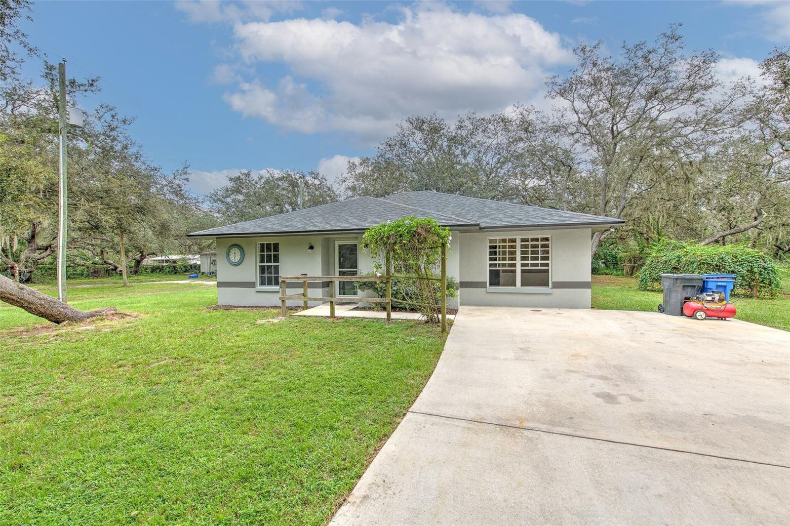 Country style living with city convenience! This 3/2 home is nestled on a full one acre wooded lot with room to clear on the back side of the property. Living area features newer easy care wood laminate flooring and high ceilings making this home live large with a flex space located off of it. Kitchen features SS appliances and pass-through to dining area overlooking lanai. Master suite with ensuite bath features a sink with tub/shower combo. Screened lanai with insulated ceiling and ceiling fan for enjoying peaceful mornings with double doors that lead you out to a 32x10 slab extension with an extra 100-watt service panel. Wooden shed on property with tie downs for extra storage. For the garden lovers there is your very own trellis of grapes! New roof in 2024 with transferrable warranty, exterior painted in 2023, new A/C 2021, solar hot water heater, solar panels installed 2018, UV light for well, Google Nest thermostat, two solar attic fans and radiant barrier ~ combined with the solar panels, you'll enjoy low electric bills and love the energy efficiency this home offers! With NO HOA and NO CDD, you can bring all the toys!