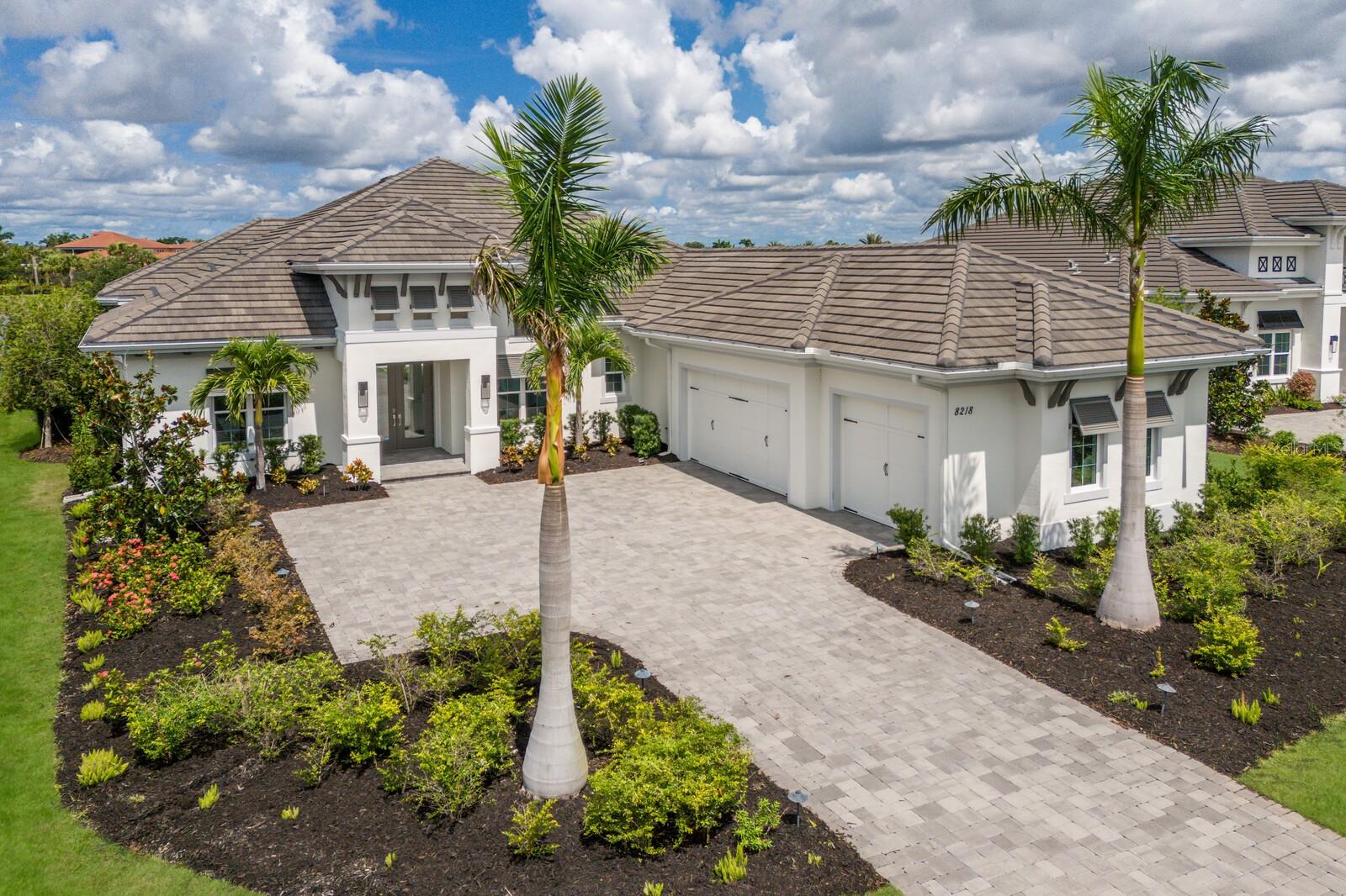 Experience sunsets over the lake from this Sterling III residence inside the exclusive gated community of The Lake Club in Lakewood Ranch. Encompassing 3,829 square feet of open one-story living, this custom Stock Home built in 2020 boasts generously sized indoor and outdoor spaces, volume ceilings, stylish finishes, and, of course, IMPACT windows/doors/sliders.
An expansive outdoor retreat elevates the Florida living experience with a panoramic screened lanai, extensive open and under cover spaces grounded with pavers, fully loaded summer kitchen with even a pizza oven, PebbleTec heated saltwater pool/spa with sun shelf, fireplace, and a serene lake view with sunsets delivered nightly.
Ten foot impact glass sliders seamlessly connect the outdoor oasis to a luxuriantly large great room, dining area and gourmet kitchen with sumptuous luxury plan vinyl crowned with soaring ceilings creating an open continuity of space. The kitchen further accentuates with white wood cabinetry, quartz counters, stainless steel appliances, and walk-in pantry.
Relax and unwind in the owner’s quarters positioned on a private wing, offering double tray ceilings, large scale windows, direct lanai access, wood flooring, two oversized walk-in closets, and an appointed spa-like bath with two vanity stations , an oversized shower, large soaking tub, and separate water closet. Family and overnight guests will appreciate the three additional guest suites, all generous in size, all with walk-in closets, two offer ensuite full baths, while the third guest room is just off the home’s fourth full bath.
An impressive club room directly off lanai beckons for entertaining with glorious views beyond, plus the residence delivers an impressive office behind double-entry doors just off the entry foyer. Other notable highlights of this all-encompassing 5,963 total square foot residence includes a brilliantly finished laundry room, a pool with auto-fill and auto-drain, all impact windows and doors, and an oversized three car garage with electric car charging station.
This newer and modern offering is the pinnacle of luxury living in The Lake Club, where residents enjoy access to a wealth of amenities, including two resort-style heated pools, Grande Clubhouse with fine dining and bar area, a fitness center, spa, tennis courts, pickleball, a playground, dog park, and services of a full-time concierge and activities director.