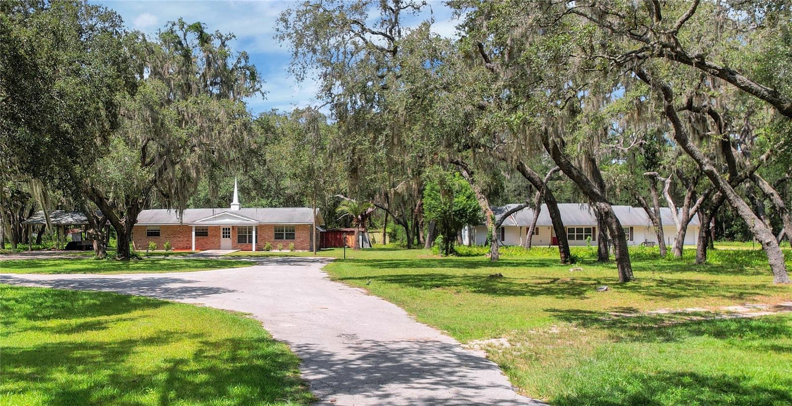 LOOKING to establish a FAMILY COMPOUND or a RENTAL OPPORTUNITY or a CHURCH with a PARSONAGE or... the sky's the limit! Welcome to this unique two single family home residential property located on 5 FENCED acres in the desirable Lady Lake area. The siding and frame home on the right was built in 2006 and is a 4 bedroom 3 bathroom with oversized garage (24x28) showcasing 1,952 square feet heated. The frame and brick home on the left side provides 1,560 of heated living space (the current status of this home is being used as a church) could be converted back to a residential home or used as a church. These homes provide a unique and rare opportunity to have your own homestead with extra living quarters on these beautiful 5 acres. This property is located within a few minutes to the Villages, shopping, doctors, grocery stores, restaurants and more! Bring your toys and animals and enjoy this gorgeous 5 acre parcel! Whether you envision a private homestead with separate guest quarters, a multi-generational living arrangement, or an investment property, this unique setup offers unmatched flexibility!