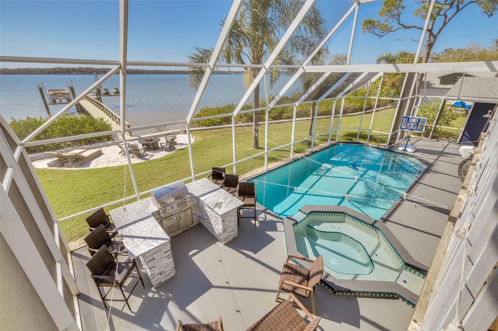 *** $100,000 Price Reduction. *** Life is good! 728 Shore Drive is a dream come true! With more than $575k in updated amenities and features, this home is the pinnacle of waterfront living in Florida. Conveniently located on a recently landscaped double lot with over 150 feet of water frontage and a brand new seawall, all boxes have been checked. Enjoy the widely sought-after western facing back yard which provides an immaculate sunset every night over the tranquil Tampa Bay water from the edge of your 100 ft. private dock. Walk out of your primary bedroom onto the large balcony overlooking the pool and the bay. Entertain your guests, pool side, while cooking your favorite meal at your pristine outdoor kitchen with built-in Blaze Grill. Relax by laying out in the setting sun on the deck of your heated saltwater pool, protected by the massive No-See-um enclosed screen! We are talking about 6 bedrooms and 6 fully remodeled baths on a 4,381 square foot split floor plan with a fully remodeled and spacious primary bedroom/In-law suite on the first floor, complete with a wet bar, a full bath with dual vanities, and a walk-in closet. The partially remodeled kitchen has new counter tops, backsplashes, appliances, and kitchen sink. The oversized garage is fully remodeled with epoxy floors, perfect for all sorts of fun activities. Key updated amenities and features include: Brand new seawall in 2022, a new 100 ft. composite dock in 2021 with a 7,000 lb boat lift and double jet ski lift, which were also both installed in 2021, 2022 new back patio and drainage system, added hurricane grade windows 2022, new driveway with "Sport Court" and RV/Boat parking in 2022, french doors and sliders installed throughout in 2021 & 2023, 2019 shingle roof, new 3 ton A/C system in 2024, and much much more. A complete features and upgrade list is available upon request! Journey right down the road to Mobbly Beach Park, with its intimate beach shore and serene nature trail. Go west on Shore Drive and enjoy a day at R.E. Olds Park and amphitheater. Golf cart friendly community makes trips around the neighborhood enjoyable. Moments away from some of the best restaurants in the area as well as the world renowned Tampa Bay Brewing Company. Oldsmar is perfectly poised between the exciting downtown Tampa experience and the beach lifestyles found across Pinellas county. Get in your boat and chart a course for the historic Philippe Park which is right across the bay. Quick access to Tampa International Airport, Clearwater Beach, and Safety Harbor. No HOA or deed restrictions! 25 MPH street. Call today for your private showing!