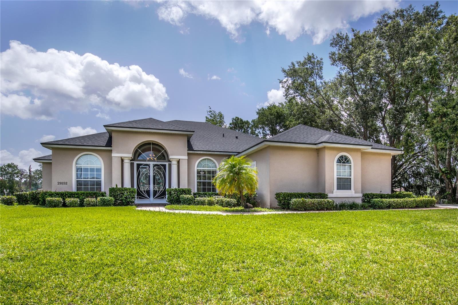 RARE WATERFRONT PENINSULA PROPERTY ON THE HARRIS CHAIN OF LAKES – 767 FEET OF WATER FRONTAGE! Dreaming of true waterfront living with space to spread out and no HOA restrictions? This one-of-a-kind 1.2-acre property in Shirley Shores offers the ultimate Florida lifestyle with 767 feet of waterfront, direct access to the Harris Chain of Lakes, and water on three sides of your private peninsula. Nestled at the end of a quiet cul-de-sac, this custom-built home combines serene privacy with easy access to shopping, dining, and local attractions.
Highlights include: Two docks, including one with a covered boat lift, perfect for fishing, cruising, or heading out for dinner on Lake Harris or Lake Dora. A spacious backyard ideal for a future pool, garden, accessory dwelling, or room to park all your toys. Majestic oak trees, natural surroundings, and neighboring luxury homes in a charming, old Florida setting. Inside, this 4-bedroom (3 + den), 2.5-bath split floor plan offers flexible living with abundant natural light and stunning views from nearly every room. The formal living room greets you with a wide picture window framing your private waterfront backyard, while the adjacent dining room offers space for special gatherings. A separate den overlooks the front yard and canal, making it a perfect home office or cozy reading room. The primary suite is your personal retreat, featuring a door to the screened lanai, two walk-in closets, an oversized en suite bath with soaking tub, and dual vanities, walk-in shower, and private linen closet. Guest suites are located on the opposite side of the home, joined by a Jack-and-Jill bathroom with direct lanai access—perfect for future pool use. A half bath near the garage and a spacious interior laundry room add convenience. The central kitchen is ideal for entertaining, offering a center island and breakfast bar, Butler’s pantry, cozy breakfast nook, and ample cabinetry and storage throughout. This home is built for comfort and long-term enjoyment with a NEW ROOF (2025) and NEW HVAC (2024). It has the added benefits of 220-amp service in the garage, Handicap-accessible interior, storage shed, and more. Lovingly maintained by its original owners, this is more than just a home—it’s a lifestyle. With direct access to the Harris Chain and room to grow, it’s the perfect escape with endless potential. Don’t miss this once-in-a-lifetime opportunity to own your own slice of paradise. Schedule your private tour today!