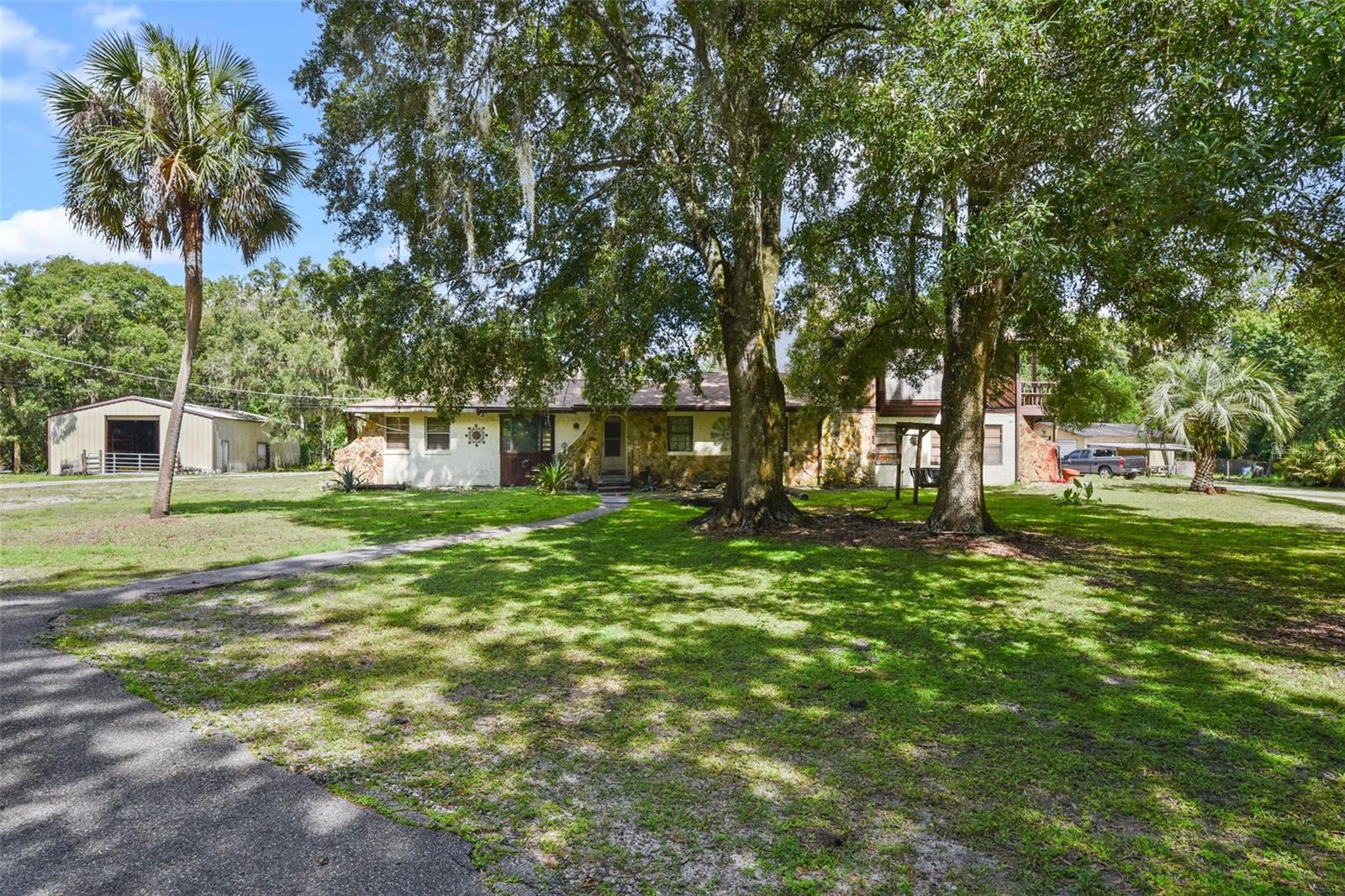 HIGH & DRY + 2021 ROOF + UPDATED ELECTRICAL PANELS + COPPER + PEX PLUMBING + STRUCTURALLY SOUND Rural Living with Endless Potential on 5 Acres! Property stayed high and dry during and after Hurricane Ian. Located in the heart of Geneva across the street from Lake Harney and within the Geneva Bubble—known for its high-quality aquifer water—this unique 4-bedroom, 3-bath pool home offers the perfect blend of privacy, space, and opportunity. As you step into the front door you'll find a large family room including a full kitchen with an exterior door out to one of your drive ways and a dining room along with an another set of exterior doors to your patio and laundry room. Down the hall are the rest of your first floor bedrooms including one of the primary bedroom plus an office space. On the other side of the hall is a second living room with another full kitchen and pantry. Upstairs is another large primary suite with additional living space, two walk in closets and room for a third kitchen if need be! In addition this upstairs suite has its own walk in suana that is operational and exterior entrance.
The home features two master suites, two full kitchens, multiple living areas, and a layout ideal for multigenerational living or an investment renovation. Interior updates are needed, mainly cosmetics, making it a great fit for investors looking for a high end fix and flip or someone who is prepared to take on a renovation to make it exactly how they dream!
Enjoy the grounds of this property with two ponds, a 2 story screened pool with a balcony over looking, full-size fenced tennis court, dog runs, chicken coops, goat coops, potting shed, and a paved circular driveway. A massive 30x60 metal building offers space for an RV, workshop, or garage, in addition to a 24x24 detached garage and 2-car carport. The property also includes a second well strictly for irrigation with plumbing already in place but will require a new well pump motor. For the horse lovers there are two designated paddocks and a fenced riding arena already in place!
This is your chance to own a versatile property in one of Seminole County’s most desirable rural areas. Cash or renovation loan preferred—schedule your showing today!"
