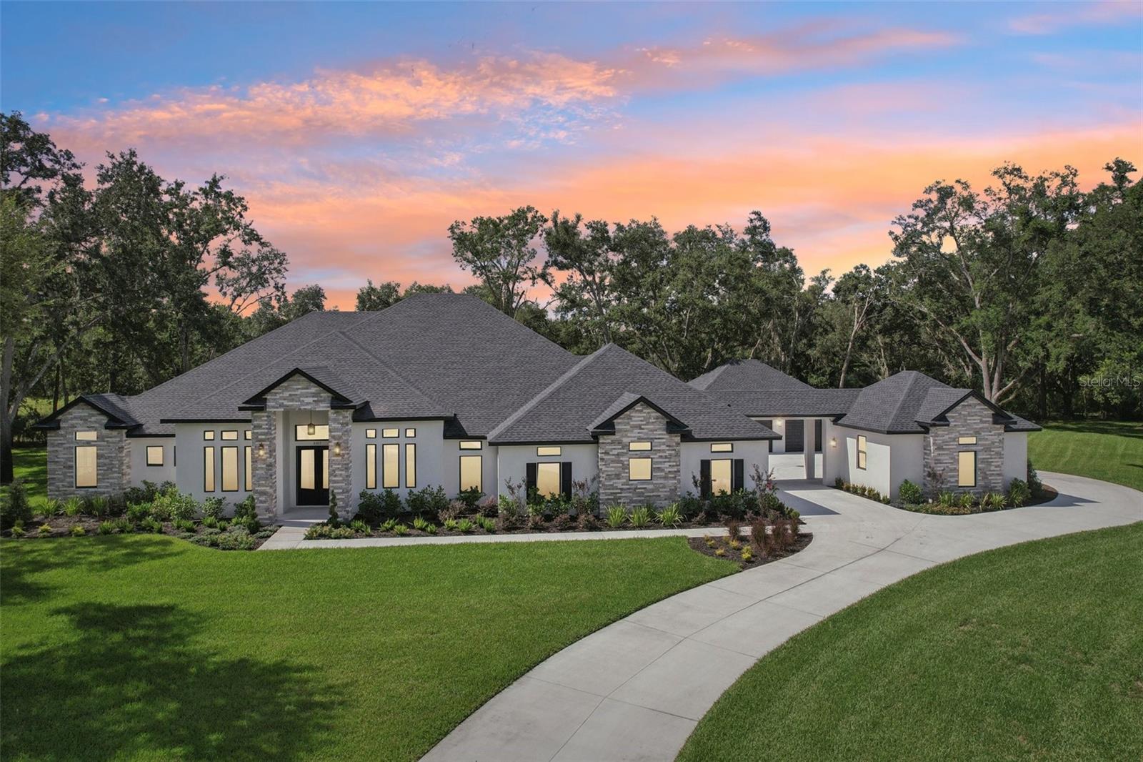 One or more photo(s) has been virtually staged. Discover unparalleled elegance and privacy in this BRAND NEW, CUSTOM-BUILT ESTATE, perfectly situated on a PREMIER 1.12-ACRE CUL-DE-SAC lot on a nature preserve within the exclusive, GATED COMMUNITY of The Sanctuary on Livingston. A masterpiece of design and craftsmanship, this 5-bedroom, 4.5-bathroom residence offers a private and serene sanctuary, where every element is designed to evoke a sense of peace and tranquility away from the bustle of daily life.
A gracefully curving driveway sweeps up from the road, joining a circular motor court that provides access to a stately SIDE-ENTRY PORTICO and the home's TRIPLE GARAGES. Step inside to an expansive OPEN-CONCEPT DESIGN, where HIGH CEILINGS and an ABUNDANCE OF NATURAL LIGHT FROM LOW-E WINDOWS create a bright and airy ambiance. Modern and durable ENGINEERED HARDWOOD FLOORS flow throughout, unifying the home with a seamless and stylish foundation.
The heart of the home is the spectacular gourmet kitchen, a chef’s dream equipped with DUAL QUARTZ ISLANDS, ELEGANT TWO-TONE CABINETRY, AND A SUITE OF HIGH-END APPLIANCES, INCLUDING TWO EXTRA-LARGE REFRIGERATORS, TWO DISHWASHERS, AND A PROFESSIONAL-GRADE 6-BURNER DUAL-FUEL RANGE. A huge walk-in pantry with custom shelving provides endless storage. Entertain with ease in the formal dining room, serviced by a chic BUTLER’S PANTRY COMPLETE WITH A REFRIGERATOR AND SINK, or craft cocktails at the family room's STYLISH WET BAR. A DEDICATED OFFICE provides the perfect space for work or study.
Retreat to your private owner’s suite, a serene sanctuary FEATURING TRAY CEILINGS AND DIRECT ACCESS TO THE LANAI. The spa-like ensuite bath is a testament to luxury, boasting a FREE-STANDING SOAKING TUB, A MASSIVE WALK-IN SHOWER WITH DUAL SHOWER HEADS, AND SEPARATE HIS-AND-HERS WALK-IN CLOSETS. The intelligent split-bedroom floor plan ensures privacy for all, with one secondary bedroom offering a full ensuite bath and another providing its own lanai access.
The luxury extends outdoors to your private oasis. A sprawling covered lanai finished with BEAUTIFUL TRAVERTINE FLOORING overlooks a STUNNING SALTWATER, HEATED POOL AND SPA. The FULL OUTDOOR KITCHEN is perfect for alfresco dining and entertaining year-round. This exceptional home is complete with DUAL RINNAI TANKLESS WATER HEATERS and generous recessed lighting throughout.
Perfectly located, this private haven offers a luxurious lifestyle with convenient access to major highways, premier shopping, restaurants, and top-tier medical facilities, with downtown Tampa just a short drive away. On top of all that, VERY LOW HOA DUES AND NO CDD make this appealing home even more desirable!