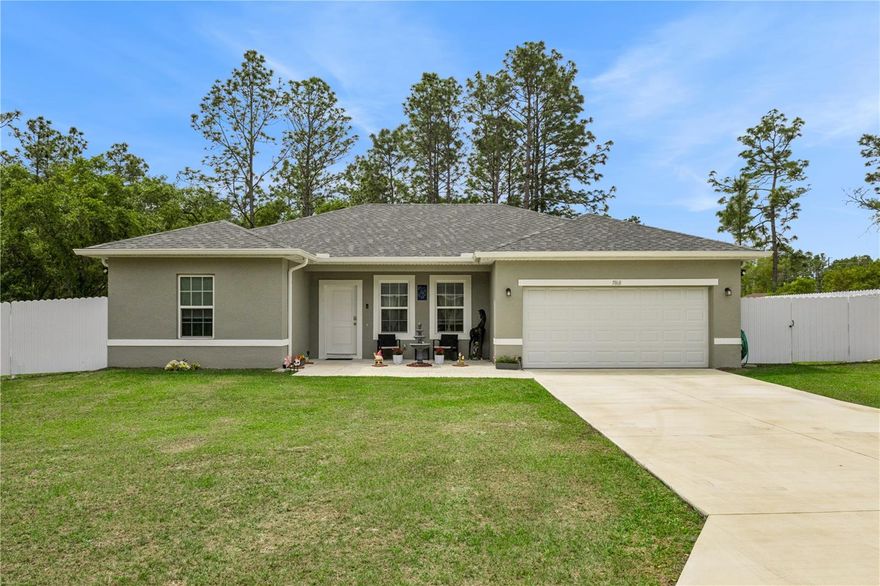 Built in 2023 on a fenced quarter-acre lot in Marion Oaks, this 4-bedroom, 2-bath single-story home delivers 1,580 square feet of open-concept living with no HOA, no carpet, and a private outdoor space that the surrounding neighborhood rarely offers. The layout opens immediately from the entry and carries an uninterrupted sight line from the living room all the way through the dining area, past the kitchen island, and out the sliding glass doors to the covered patio beyond.
The living room connects without interruption to the dining area and kitchen. Ceramic tile runs throughout every room in the home. The kitchen is finished with espresso shaker cabinetry, speckled granite countertops, a stone mosaic tile backsplash, and a full suite of stainless steel appliances including a French door refrigerator, electric range, over-range microwave, and dishwasher. An island with an undermount double-basin sink, a gooseneck pull-down faucet, and breakfast bar seating for three anchors the space, with triple pendant lighting overhead and a closet pantry just steps away. The dining room runs open alongside the kitchen in a continuous line toward the rear of the home, the sliding glass doors at the far end framing the patio and yard beyond.
The primary suite is privately positioned at the rear of the home with a walk-in closet and en suite bath. The bath features a walk-in shower wrapped floor to ceiling in large-format marble-look tile with a decorative glass mosaic accent band, a frameless sliding glass enclosure, and a dual-sink vanity with espresso shaker cabinetry, granite countertops, and satin nickel fixtures. Three secondary bedrooms are clustered in their own wing on the opposite side of the home, each with ceramic tile, a ceiling fan, and a built-in closet, with two of the three measuring over 12 feet by 12 feet.
The covered rear porch extends to a two-tone paver patio, a shaded outdoor space connected directly to the main living area through the sliding glass doors. The fenced yard stretches across the full depth of the quarter-acre lot, enclosed on three sides by white vinyl privacy fencing, with a mature wooded tree line rising behind the rear fence that adds natural privacy and an open-sky backdrop without the maintenance. A storage shed at the far end of the property provides additional covered utility.
Located in Ocala with easy access to SR 200 and I-75, this home is minutes from Silver Springs State Park, the World Equestrian Center, and the full range of Ocala dining, shopping, and outdoor recreation. Built in 2023 with a home warranty included and no HOA fees or restrictions, it offers a combination of condition, outdoor space, and ownership freedom that is genuinely hard to find in Marion Oaks.