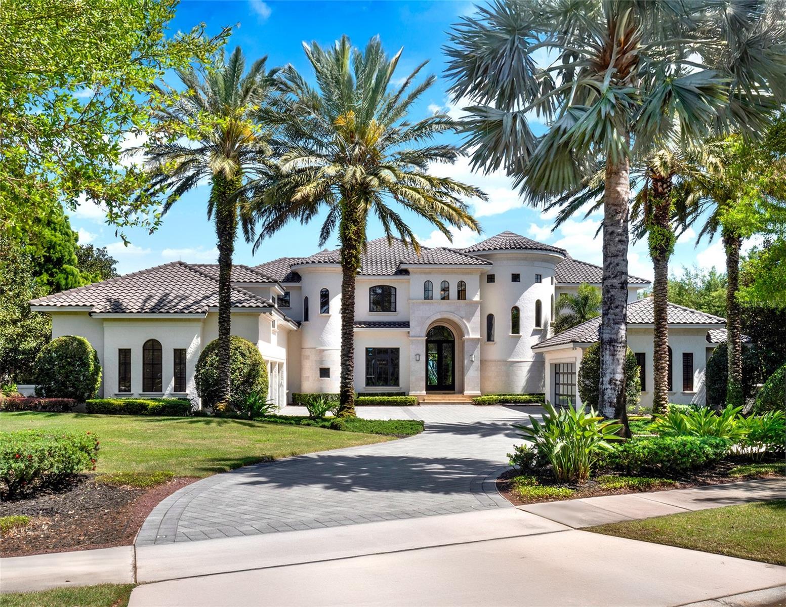 Experience luxury lakefront living on a grand scale in this custom-built Modern Mediterranean estate on Lake Tibet, part of the pristine Butler Chain of Lakes. The three-story residence spans 9,571 square feet of living space on over 2.2 acres in the guard-gated community of Keene’s Pointe in sought-after Windermere. Built by Goehring & Morgan, this architectural masterpiece offers refined craftsmanship, exquisite details and seamless indoor-outdoor living with stunning water views from almost every space. The 26-foot grand entry sets the tone for soaring handcrafted coffered ceilings, travertine marble and mahogany wood floors, custom cabinetry, designer interior and exterior finishes and an open floor plan. Inside you'll find six bedrooms, five en suite, nine baths, formal living and dining rooms, wine cellar, family room, captivating saltwater aquarium, game room, lounge/loft, two offices, a mudroom, and a home theater constructed of concrete block to also serve as a safe room. The chef’s kitchen is outfitted with Sub-Zero and Dacor appliances, Esmeralda Brazil granite countertops, LED lighting, a large walk-in pantry, a prep kitchen with additional appliances and a built-in Miele coffee station with beverage refrigerator. The owner’s retreat features a private sitting room, fireplace, wet bar, oversized custom closet, spa-like bath and a covered balcony with breathtaking lake views. A spiral staircase leads to the third floor, the highest elevation in Keene’s Pointe, where you’ll find a private study and an observation deck. Massive sliding doors open to a spectacular outdoor living space with retractable screens, tongue-and-groove ceilings, fireplace, TV and a full summer kitchen with Viking gas grill, sink and refrigerator. The resort-style saltwater pool features a Beadcrete finish, sun shelf, lazy river, slide, grotto, swim-up table and stools, island planter with palm trees, spa and dramatic water, fire and lighting effects. A putting green and built-in trampoline complete the backyard oasis. One of only two, two-story docks in Keene’s Pointe, the home's private boathouse includes two boat slips with lifts and touchless covers, plus a floating dock for jet skis. Additional features include an elevator, in-floor vacuum system, attached in-law suite with private entry plumbed for a future kitchen, two garages with room for five cars and a gated dog run. The barrel tile roof, stone entry columns, motor court with fountains and professionally designed landscaping further elevate the estate. Keene’s Pointe offers access to the Butler Chain of Lakes, a 250-acre Jack Nicklaus Signature golf course, the Golden Bear Club, resort-style pool, tennis courts, fitness center, multiple playgrounds and a clubhouse for private events. Windermere offers small-town charm with proximity to downtown Orlando, fine dining, world-class shopping, championship golf courses, top-rated schools, international and private airports, and theme parks.