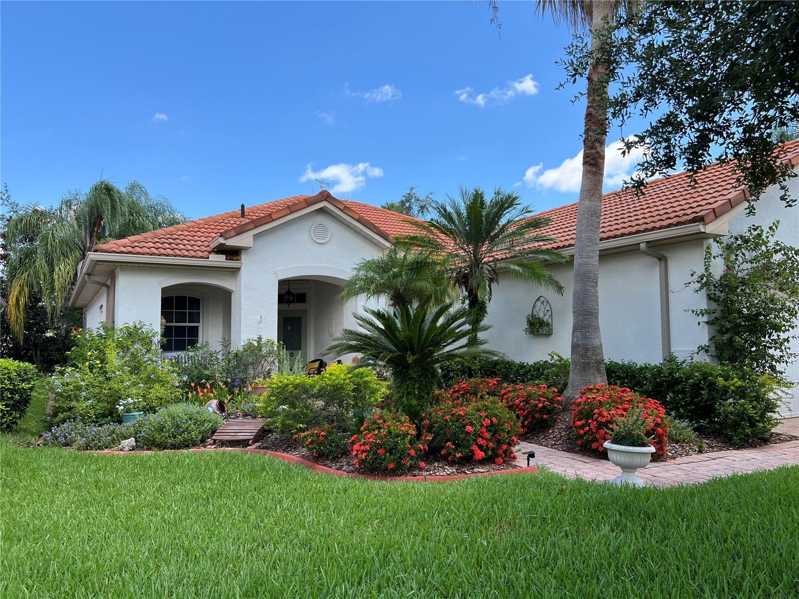 Beautifully maintained home in Solivita. Gorgeous landscaping and flowers around the stone paver driveway and walkway lead you to the front porch, which is covered and has space for seating. Inside, see the tiled flooring in the living room and look out toward the sliding glass doors to the back screened porch and private back yard with lush landscaping. There are French doors to the den/office, which could easily serve as a bedroom, with the addition of a closet. The living room leads to the dining room which also has a window view of the yard, plus sliding glass door access to the back screened porch. As for the kitchen, all appliances are less than 2 years old and all will convey. The oven has a popular air fryer feature. There is a closet pantry, high breakfast bar with seating, and lots of light cabinetry. The primary bedroom looks out to the back yard, and has a private bath with vanity seating, and glass-doored tiled shower. The second bedroom has its own bath, with tub/shower. The inside laundry room leads to the garage, with two walls of built-in cabinets for lots of storage area. Inside the garage is space for one car, plus the golf cart, which will convey with the sale! The home has high ceilings, and crown molding throughout, even in the closets. The back porch is screened-in for shaded bug-free enjoyment of all seasons. There is a flowing water fountain in the back yard, watch for bathing birds! Flooring is all easy-care ceramic tile, except for the bedrooms and den, which have wood-look laminate flooring. There is an intercom system throughout the home, also lightning protection and hurricane shutters. The roof is long-lasting clay barrel tiles, AC was replaced 5 years ago, water heater 10 years ago, and the home's exterior was recently painted. The HOA will pay for your cable TV and internet via Blue Stream Fiber Optics! While out in the community notice all the wildlife, deer, cranes, and water birds. There is a lot to do here in Solivita, a 55-and-better community! Restaurants, shopping, 14 pools, one is even indoors, two golf courses, a ballroom, exercise classes, pickle ball, activities, an indoor track, so many clubs. Hop in your golf cart and see! There is a pool and lake one block away from the home. You will stay as busy as you choose to be here in Solivita!