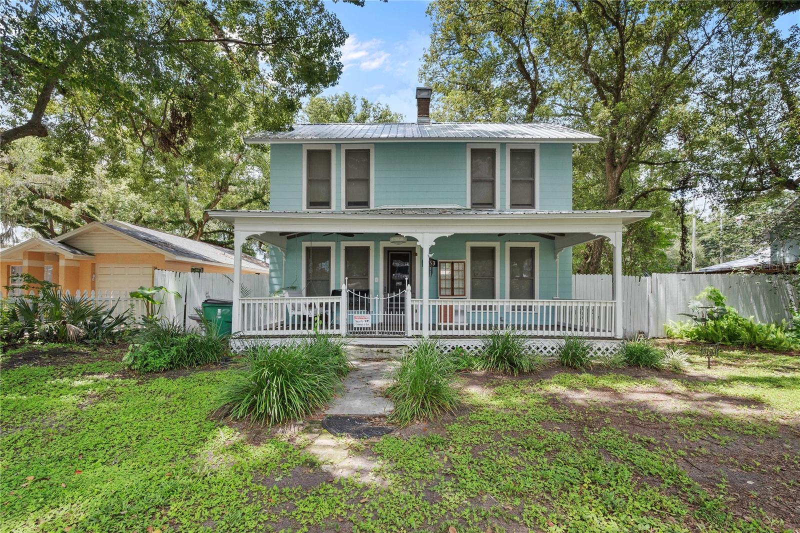 NEW TO THE MARKET! LOVELY HISTORIC ERA HOME with a BONUS GUEST HOME ON A BEAUTIFUL TREED CITY LOT! Features of this great property include a main dwelling, two story 1920 historic constructed 3 bed 2 bath home with approximately 1,624 sq ft of living space. As you pull up, you will notice the great curb appeal with a large elevated front porch approximately 22' long and a wonderful swing bench to enjoy mornings or evenings on. Enter the home and the appeal will hit you with vast vertical windows, pine wood flooring, wooden ceilings, and a gorgeous kitchen featuring GE CAFE' appliances. The kitchen also features a bar stool height countertop long enough to accompany four stools for seating, and room for a breakfast table as well. Enjoy making & eating meals while overlooking your beautiful backyard from more windows in the kitchen. The living room has a built in decorative fireplace and built in shelving. The guest bathroom downstairs features a cast iron tub with hand shower attachment. A formal dining area is adjacent to the kitchen area, as well as a large walk in closet pantry and indoor utility room with washer/dryer hookups and plenty of cabinet space. Step down into the bonus room area that measures approximately 18' x 9' which can be used for more living space, gym or play area, home office, and more! One bedroom is located downstairs again with vast vertical windows and pine flooring that is ready to be refinished to its original glory, head upstairs for the other two bedrooms and upstairs bath room that features a tub/shower combo. A fabulous outdoor paradise awaits with a vast fenced in yard, built in paver firepit with cooking grate, above ground pool, and beautiful trees that provide a good mixture of both shade and sun throughout the day! Then check out the detached studio style guest home that features a wrap around open porch & retractable awnings over two french door entrances. The guest home has a living room, kitchen with sink and flat cooktop, full bath with shower, and a dining area on the first floor. A second floor loft can be used for a bedroom area for the younger ones or makes for great a/c storage area too. Metal roof on the main home was replaced in 2019. Main home has both central a/c and window units for the dining and bonus room areas. The guest home features a mini-split ac system. There is also a metal outdoor shed measuring approximately 13' x 9 with a roll up bay door and electric. This is an amazing home and property for the buyer that doesn't want to be in a cookie cutter subdivision with HOA or CDD fees. Excellent close walking proximity to vibrant Downtown Zephyrhills Mainstreet that features entertainment, restaurants, events and festivals! The seller discloses the following: active drywood termites were discovered in guest bath area, and guest home and bonus room on main home were not permitted however seller is currently seeking permitting with City. A great value for all this at a purchase price offering of $425,000.00! Schedule your tour today before it sells!