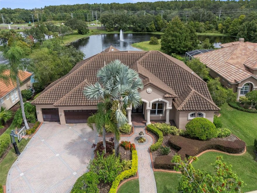 Welcome to Cypress Cove—an exclusive gated enclave of just 28 estate homes, where opportunities to purchase are exceptionally rare. This WATERFRONT 4-bedroom residence with office and upstairs bonus room offers 3,715 sq. ft. of thoughtfully designed living space, ideal for both elegant entertaining and everyday comfort.

A brick-paver driveway leads to the grand entry, where rich wood flooring, formal living and dining rooms, and a well-appointed wet bar with multiple refrigerators create a warm and inviting first impression. The home’s desirable three-way split floor plan provides outstanding flexibility for large households or multi-generational living.

The oversized primary suite is a true retreat, featuring plantation shutters, tranquil pool and pond views, and a beautifully updated bath with a walk-in shower, dual vanities, and an expansive custom closet. The chef’s kitchen offers abundant cabinetry and bar seating, opening seamlessly to the impressive great room with a gas fireplace—perfect for relaxed gatherings.

Two guest bedrooms with newer carpet and a full bath are conveniently located off the great room. The private in-law suite includes its own sitting area, bedroom, full bath, and direct backyard access—ideal for long-term guests or extended family. Upstairs, a massive bonus room with a walk-in closet and full bath provides endless possibilities: game room, home theater, fitness studio, or additional guest space.

Step outside to your personal tropical oasis. The screened, heated pool features a spillover spa, updated jets, and a color-changing light display (2020), all surrounded by a brick-paver deck. The fenced yard overlooks a serene pond teeming with wildlife, offering a peaceful and private backdrop.

Notable updates include:  
• Refrigerator (1/2026)
• Roof (2018)
• A/C units (2024, 2014, 2021)
• Pool pump (2023), chlorinator (2023), pool/spa heater (2022)
• Carpet (2020)
• Water softener (2021)
• Motorized shades (2020)
• Exterior/paver lighting & fountain (2021)
• LED recessed lighting with 5 color settings (2020)

All of this in a prime Tarpon Springs location—close to dining, shopping, and an easy commute to Tampa. East Lake High School is just a short walk away.

A rare opportunity to own in sought-after Cypress Cove—this exceptional waterfront home is not to be missed.