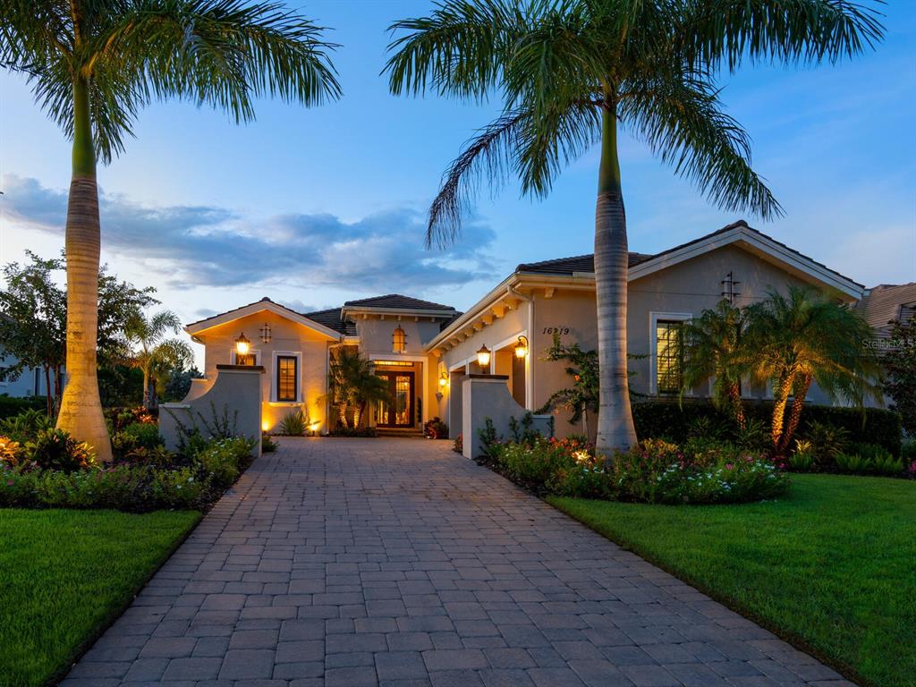 Luxurious elegance begins at the handcrafted iron double front doors of this 2018-built more than 2,800 square foot home nestled in the Lakewood Ranch community of The Lake Club. One step into the foyer and you’ll feel right at home, greeted by the hardwood flow of Saddle Brook glazed porcelain tile by Dal-Tile. The cozy yet abundant feel continues through the open floorplan, highlighted by soaring tray ceilings with recessed lighting in the foyer, office, dining room, great room and master bedroom. The kitchen serves as the focal point of the home with staggered wood cabinetry with soft-close drawers and doors, stainless steel appliances, designer glass tile backsplash, a walk-in pantry and elegant quartz countertops. Bring the charm outside on the extensive pavered lanai complete with outdoor kitchen featuring grill and hood with a sink and refrigerator. The tropical greenery is the perfect touch surrounding the heated pool and spa as you enjoy tunes from the speakers of your Sonos sound system. Wind down in your master suite with a spa-like bathroom boasting stand-alone tub, double sinks, quartz counters and exquisite lighting. You’ll be the place to host the company of friends and family as each of the two guest rooms feature its own ensuite bathroom, and the three-car garage with epoxy floors leaves plenty of room for others to park on the lengthy pavered driveway. Whole-home features include a water purifier, filter and softener, standard, as well as micro-irrigation system, a whole-home generator and impact glass windows and doors with Plantation shutters throughout. One of more than 700 homes in the village of The Lake Club, enjoy community amenities including the spectacular 20,000-square foot Grand Clubhouse, featuring a lively calendar of social events all while just a short drive to Sarasota’s downtown shopping and dining, as well as its award-winning beaches.