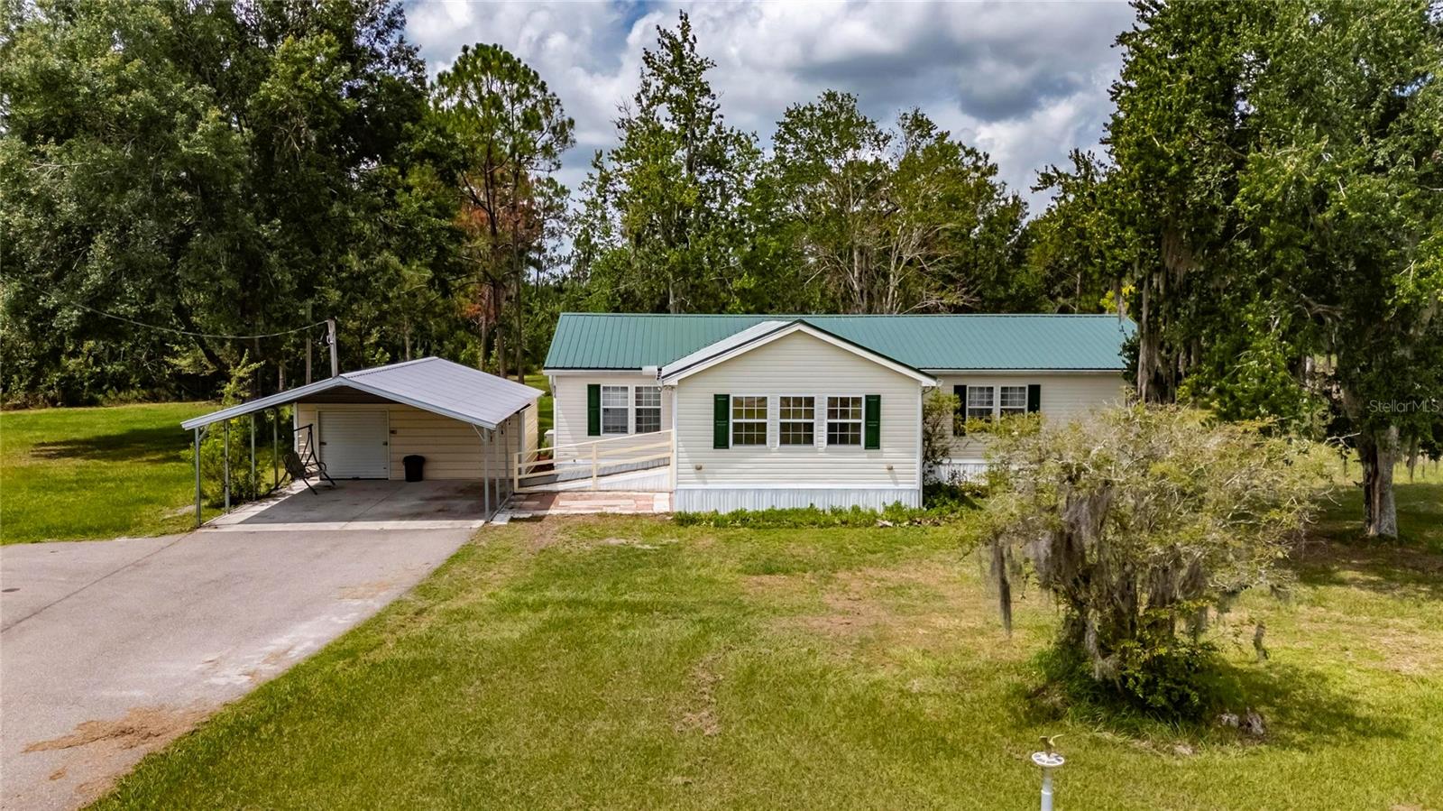 Come take a look at home you can keep all your toys and work equipment. 6.5 acres of fenced land is zoned for Residential & Agriculture. Think of all the things you can do here: store your RV, trailer, farm equipment, raise animals from chickens to horses or build your dream home. The 3 bedroom, 2 bathroom mobile has been converted into a 2/2 for more living room space but can easily be converted back with just one wall. The home has a brand new metal roof, new skirting and the foundation and straps inspected and some replaced. County records have 1456 sq ft but doesn't include the beautiful x 19ft X 14ft (266 Sqft) pine panelled front room that has an AC unit but is not heated (do you need more heat in Florida?) That's 1,722 Sqft under the roof. The property is fully fenced. Includes an enclosed well house, large carport with a storage shed & a long driveway that gives easy access to any vehicle & allows lots of room for parking. Last but not least a mechanic's dream - a 42 x 20 covered workspace which features a concrete slab floor, 8x40 trailer and a loading ramp for loading heavy equipment. The workspace can hold any type of vehicle including, work trucks, heavy equipment, boats & RVs. Enjoy small town living with access to everything with Disney being minutes away!