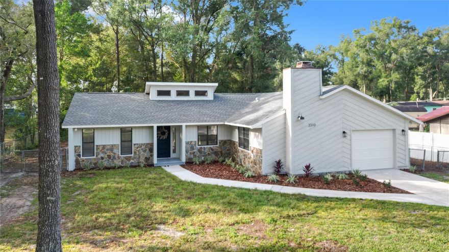 One or more photo(s) has been virtually staged. FULLY REMODELED MODERN HOME for you to enjoy! Come see this 3 bed/ 2 full bath, 1,415 square foot concrete block home nestled on a private wooded .36 acre lot with NO HOA! This home has high ceilings, a brand new kitchen with white soft-close cabinetry, quartz countertops, black hardware, Whirlpool stainless steel appliances- and, both a living and family room space to spread out! A big front yard, plenty of space to park, and a 21x13 ft. deep garage greet you. Enter into a great room with soaring ceilings, brand new French doors leading to the spacious backyard, and an airy fan hung high. This is a true split plan with 2 bedrooms and a bathroom with a tub on one side of the home, and a primary bedroom suite on the other side of the great room. The 12x14 ft. primary bedroom is large enough to fit a King-sized bed, has modern tile, a pretty white vanity, a step-in shower, and walk-in closet. The open-concept kitchen leads into a second living area, home to a cozy wood-burning fireplace with floating mantle, and a spacious breakfast nook to your right. A brand new roof (August 2023), fresh interior and exterior paint, brand new luxury vinyl plank floors, all new cabinetry, sleek light fixtures, garage door and opener kit, new blinds, smoke detectors, and fresh SOD and landscaping make this home feel brand new! New plumbing/ shut off valves, a new 40-gallon water heater, and a 150 AMP electrical panel provide for a clean 4-point for your insurance coverage. Septic pumped 10/23. The deep backyard has gorgeous trees! Just a minute from Pearl Britton Plaza with newly renovated Publix. Settle in to your new home for the holidays!