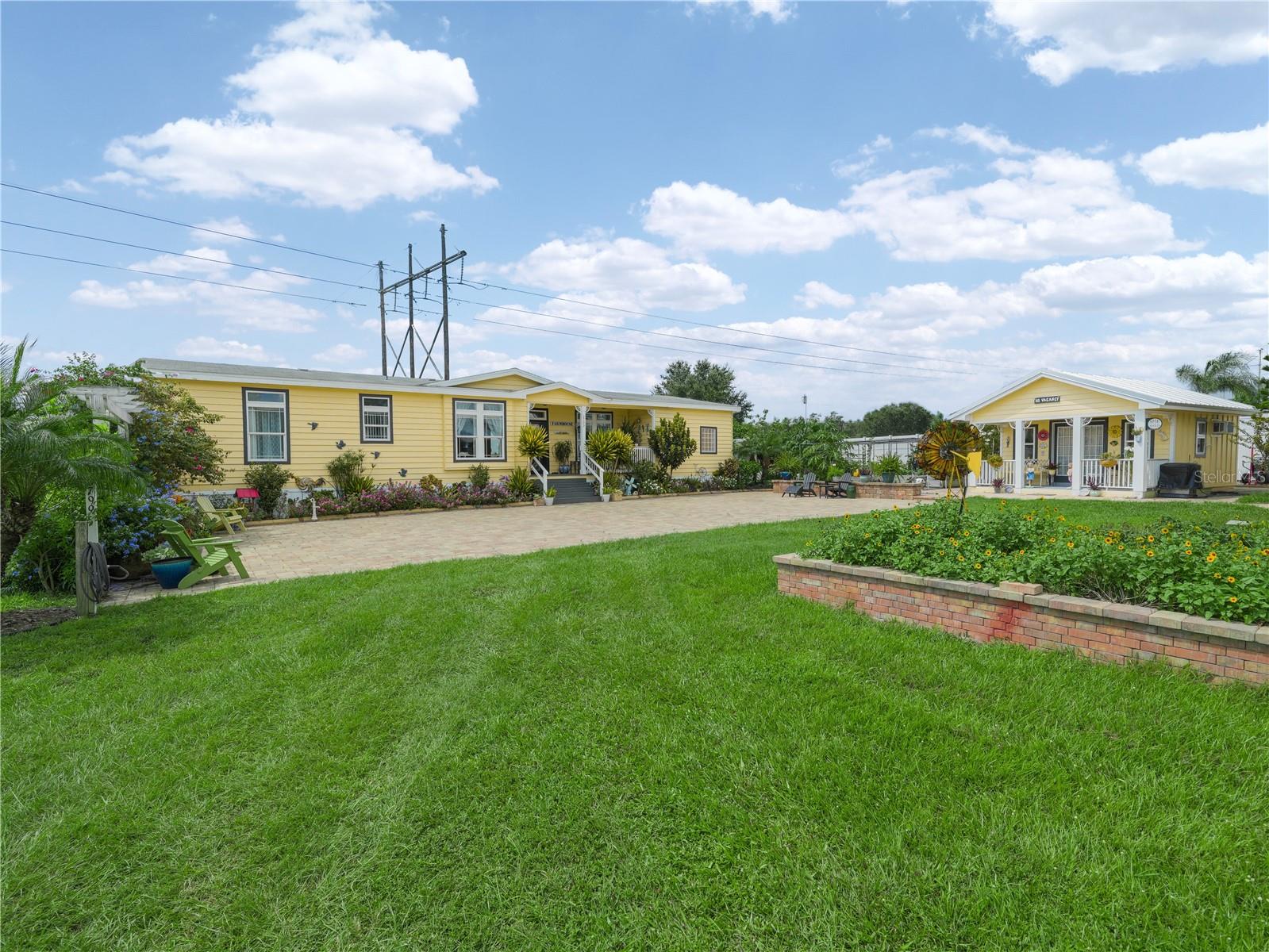 Discover a one-of-a-kind, fully fenced estate offering 3 beautifully landscaped acres with breathtaking lakefront views. This rare property combines privacy, versatility, and modern comfort, making it perfect for multi-generational living, a private compound, or a unique investment opportunity. Main Home: 3 Bedrooms/2 Bathrooms. Luxury wood laminate flooring throughout, Tray ceiling with crown molding in living area, Updated kitchen with tile flooring, solid wood cabinetry, and stainless-steel appliances. Renovated bathrooms with tasteful finishes. Spacious laundry room with front-load washer/dryer, sink, and built-in cabinetry. Outdoor living spaces: screened lanai, raised wood deck with built-in gas grill, and lower paved patio overlooking the lake. Additional Living Spaces: She Shed / Tiny Home: Bedroom/living area with kitchenette and full bathroom, Outdoor shower—perfect after gardening or lake activities. Wood Barn / Man Cave: Fully finished lower level with epoxy floors, living area, kitchenette, full bath, and storage closets, Custom cedar-lined bonus room with handcrafted double wood doors (ideal for office, guest room, or game room), Barn-style garage door with 20-ft ceilings—perfect for RV, boat, or multiple vehicles. Upstairs: 2-bedroom apartment with wood laminate flooring, cozy living room, and private balcony. Steel Garage/Workshop & Separate Storage Shed: Ample space for tools, equipment, and recreational gear. Property Features: In total: 7 bedrooms | 4 bathrooms | 4 living areas. Over 7 outdoor spaces: patios, decks, balconies, and lanai. Fruit trees and enclosed vegetable garden for green thumbs. Modern upgrades: hurricane-ready generator, whole-property water filtration, security system with cameras & motion lighting, and coded electronic entry gate. Whether you’re looking for a vacation retreat, multi-generational home, or income-generating property, this estate is designed to fit your lifestyle. Don’t miss your chance to own this rare lakefront gem—schedule your private showing today!