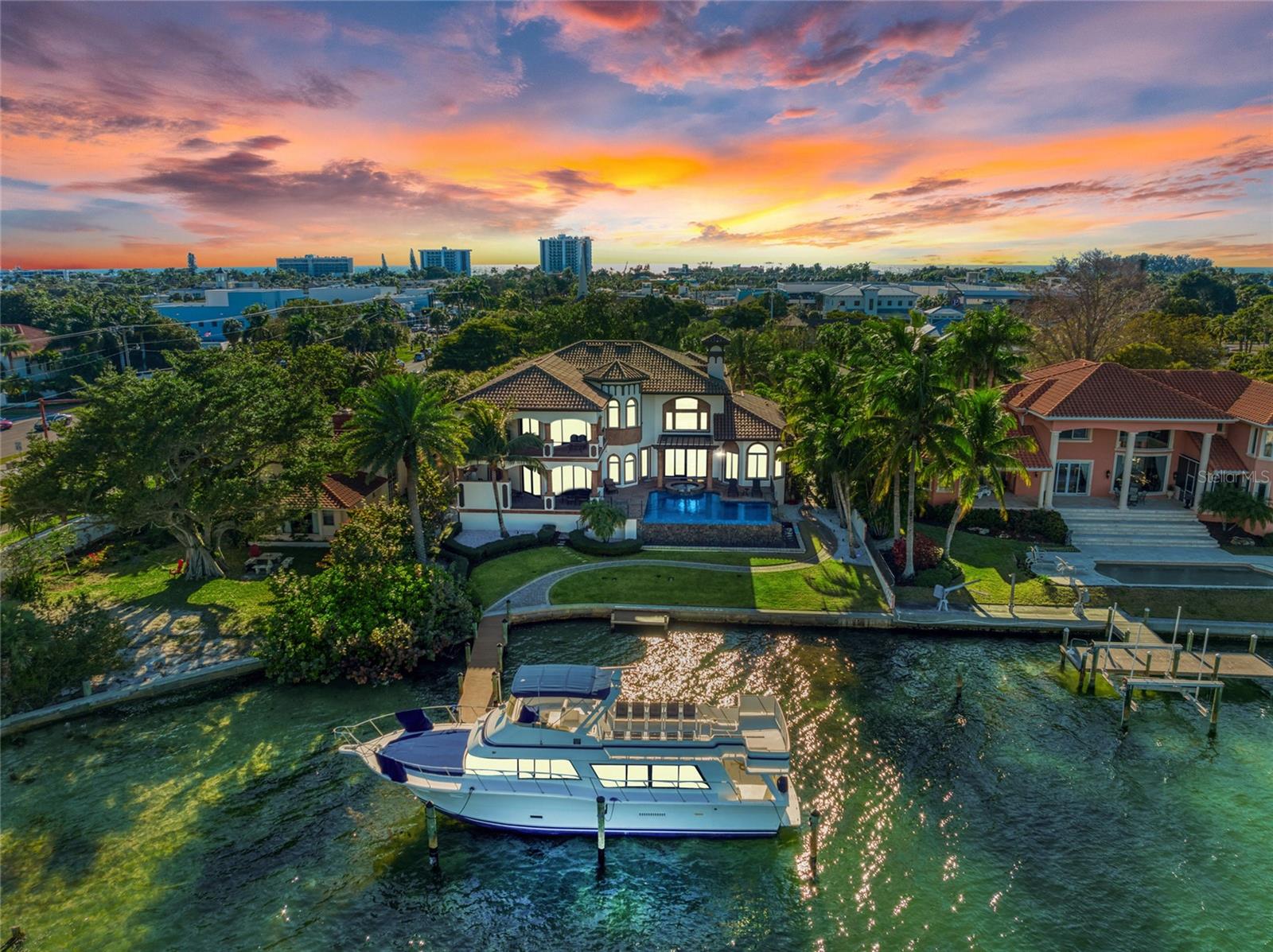 This St. Armands bay front home is a boater's paradise located in between two of Sarasota's largest passes with crystal clear waters and quick access to the Gulf of Mexico. Positioned between downtown Sarasota and the Lido Key Beaches, this residence has very rare, deep-water dockage to accommodate larger yachts with room for jet skis and an additional boat without blocking the mile-wide views. The architecturally designed home on a double lot, was extensively refreshed in 2020 to enhance a casual, yet luxurious feel. Entering through the gates, you will appreciate the many details, finishes, and materials throughout, including the imported Cantera stone. As you enter through the mahogany double doors into the great room with fireplace, open staircase and wet bar area, you appreciate the expansive views of the double-edged infinity pool and spa overlooking the bay. Designed for entertaining, the chef-inspired gourmet kitchen with Wolf and Sub-Zero appliances, includes two hammered stainless-steel sinks as well as dual dishwashers which can handle everyday family dinners to lavish parties. Enjoy your meals in the separate dining room, eat-in nook or the multiple outdoor spaces. The private, first floor master suite has its own wet bar, sitting area overlooking the pool and bay, walk-in closet and spa-like his and her bathroom with soaking tub, and double entry, multiple jet shower that will complete your home-spa experience. With three additional en suite bedrooms on the first floor there is plenty of space for a large family or guests. The garages offer three-car ground floor parking, or you can utilize a lift system to house up to six vehicles. Additional features include an elevator, outdoor summer kitchen, indoor/outdoor state of the art sound system with Apple I-Pads, multiple zone air conditioners, Advantage lighting and security systems. The open plan on the second floor includes a media/game/billiard room with lit quartzite wet bar and bay front sitting area. The large outdoor terrace provides spectacular views of the bay and downtown Sarasota while watching dolphins, birds and fish playing in the emerald-green waters. You will also find a library/sitting area along with another master suite, luxurious bath, and private balcony that overlooks famous St. Armand's Circle. The executive office has sweeping water views along with a separate 1,000 bottle temperature-controlled wine room. The spacious pool deck has plenty of room for relaxing, dining, swimming and lounging. Walk down to the dock, kayak and paddleboard launch on 100 ft. of bay frontage; perfect for casting a fishing line. You can have it all in this very special home within walking distance to St. Armand's Circle, Lido Beaches and downtown Sarasota, where you can enjoy upscale dining, shopping, live music, theater, art galleries and so much more!