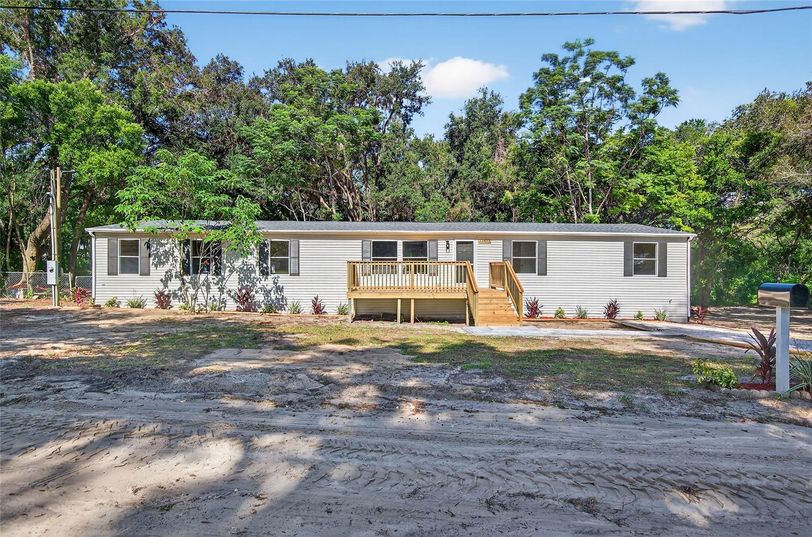 Welcome to your beautifully renovated home at 12929 Williams Rd in charming Dade City, Florida! Situated on a spacious 0.75-acre lot, this stunning doublewide offers ample room both inside and out, perfect for families seeking comfort, versatility, and modern convenience. Featuring 4 generous bedrooms—including two primary suites ideal for accommodating in-laws or guests—and 3 stylishly updated bathrooms, this home provides a welcoming atmosphere with elegant upgrades throughout. Step inside to find a breathtaking open kitchen with gleaming countertops, white shaker cabinetry, modern stainless-steel appliances, and a spacious center island ideal for gatherings. Adjacent to the kitchen, natural light floods the living space, highlighting the new flooring, tasteful finishes, and contemporary fixtures that flow seamlessly throughout the home. Both primary suites offer private retreats, each boasting luxurious bathrooms with beautifully tiled walk-in showers, creating inviting spaces to unwind. The additional bedrooms and bathrooms have been meticulously updated, ensuring comfort and practicality for family and guests. Enjoy the tranquility and privacy of your expansive yard, ideal for outdoor entertaining, gardening, or simply relaxing. The property also includes multiple outbuildings and a barn with a loft (unfinished), perfect for extra storage, workshops, or hobby spaces. Located in a peaceful setting yet conveniently close to local amenities, schools, and shopping, this home combines rural charm with modern living. Don’t miss the opportunity to call this remarkable property your own—schedule your showing today!