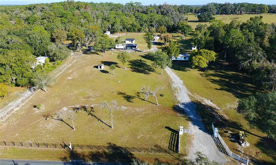Updated 5-acre property in Brooksville, Hernando County, offering multiple renovated residential structures on fully fenced, agriculturally zoned land with no HOA or CDD restrictions. The parcel includes three remodeled residences: a block-constructed 1-bedroom/1-bath home with a flex room that could be used as additional sleeping space; two 3-bedroom/2-bath double-wide mobile homes, each fully updated; a block garage with updated interior finishes and utility sink equipped with electricity and water; and an additional utility/storage building. Each residence has independent infrastructure, including its own postal address, individual electric meter, separate septic system, central air conditioning, exterior hose bibs for connecting hoses, and exterior electrical outlets for equipment or outdoor use. The property has a well as a water source. Recent property-wide improvements include new roofing installed in November 2025 on the block home and garage, updated kitchens and bathrooms throughout all residences, fresh interior and exterior paint, updated lighting and fixtures, contemporary ceramic tile flooring in multiple structures, waterproof rigid-core luxury vinyl flooring with cork underlayment in one residence, additional exterior lighting throughout the property for nighttime visibility, and gated main entrance with extended gravel driveway providing access to all structures. The land is fully fenced and includes cleared open acreage suitable for parking, equipment storage, gardening areas, workshops, livestock, and other agricultural uses subject to Hernando County zoning guidelines and permits. The property layout provides spacing between structures, offering flexibility for various occupancy configurations. Conveniently located near US-19 and Cortez Boulevard with access to Weeki Wachee Springs, parks, commercial centers, and essential services. Showings are recommended to fully appreciate the layout, renovations, and acreage this property offers.