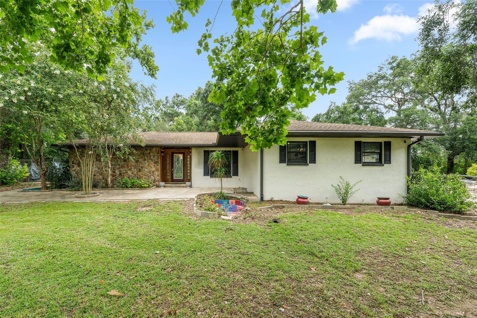 **MOTIVATED SELLER** Escape to your private paradise! This stunning 3-bedroom, 2-bath estate in Dade City offers the best of tranquil country living with modern luxury. Nestled on over 8+ serene acres at the end of a private road, this retreat has been meticulously renovated throughout. Enjoy the comfort and flexibility of two luxurious master suites, including a grand addition completed in 2019/2020. The heart of this home is the gourmet kitchen, featuring gleaming granite countertops, stainless steel appliances, and a convenient warming oven. Worry-free living is assured with a newer roof (2019/2015), updated AC (2019), and a new water heater (2022). Gleaming porcelain plank tile floors flow throughout (2019), complemented by updated ceiling fans and recessed lighting. Relax in the spacious living room under vaulted 12' ceilings, cozying up to the beautiful wood-burning fireplace with slate rock tiles. The lavish master bath boasts a refreshing walk-in shower and dual sinks. Step into the delightful 15x46 sunroom, offering picturesque views of the newer private saltwater pool (2019) – a true oasis for relaxation and entertaining. The expansive 8+ acres are fenced and cross-fenced, showcasing magnificent oak trees and lush bamboo, creating a truly secluded haven. Practical features include a whole-house propane generator and a versatile 1200 sq ft separate garage/dog kennel with its own electric meter. Enjoy the perfect blend of peaceful country living with the convenience of being just 3 miles from I-75 and a short 30-minute drive to Tampa.