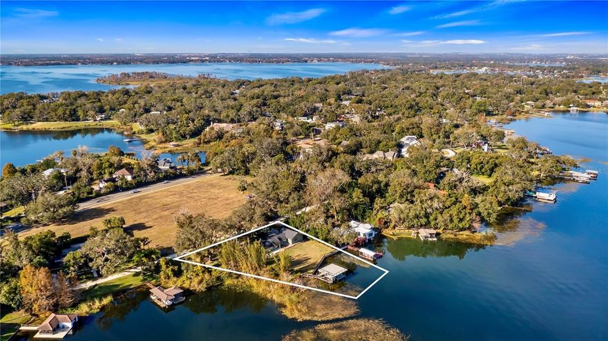 One or more photo(s) has been virtually staged. Back on market — buyer’s home sale contingency did not clear. Inspection and appraisal were completed satisfactorily, no fault of the seller or property. Welcome to an extraordinary lakefront retreat on the prestigious Butler Chain of Lakes in Windermere. On a rare 1.43-acre double lot with over 200 feet of prime shoreline on Lake Down, this exquisite residence offers a lifestyle defined by luxury, privacy and breathtaking natural beauty. Surrounded by century-old oak trees and lush tropical landscaping, this elevated single-story home combines timeless Florida architecture with sophisticated modern renovations, creating a unique offering in today’s Windermere real estate market. Spanning 2,681 square feet of impeccably designed living space, the home features an open concept floor plan enhanced by floor-to-ceiling windows that frame panoramic water views from nearly every room. The newly remodeled chef’s kitchen is a masterpiece, outfitted with custom cabinetry, stone quartz countertops, high-end stainless appliances and a generous walk-in pantry. Luxury vinyl plank flooring, designer fixtures, and a stunning wood-burning stone fireplace add warmth and character to the spacious living and dining areas. The luxurious primary suite is a private lakeside sanctuary, offering two oversized walk-in closets, floor-to-ceiling windows, and a spa-inspired contemporary bath with dual vanities and a glass-enclosed walk-in shower. Two additional bedrooms, a flexible home office, and expansive living spaces ensure comfort for family and guests. Every inch of this home is designed to celebrate Florida’s indoor-outdoor lifestyle, with sliding glass doors leading to a newly constructed oversized deck ideal for entertaining, dining and sunset watching. A standout feature of this property is the rare, grandfathered two-story boathouse complete with a private dock and boat lift, ideal for launching your watercraft onto the interconnected lakes of the famed Butler Chain. Enjoy world-class boating, fishing and watersports right from your backyard. No HOA restrictions provide the ultimate freedom to personalize your estate. Just minutes from downtown Windermere’s charming boutiques, cafes, farmers market and parks, and a short drive to Orlando’s luxury shopping, fine dining, championship golf courses and internationally renowned theme parks, this exceptional property delivers an unmatched blend of serenity and accessibility. Zoned for top-rated Orange County schools, including Windermere Elementary, Gotha Middle and Olympia High School, and positioned in proximity to Orlando International Airport and major highways. This once-in-a-lifetime offering is ideal for those seeking the ultimate Florida lakefront home, a rare Windermere double lot and access to the elite Butler Chain of Lakes lifestyle. Whether you are seeking a full-time residence or an exclusive vacation retreat, this Windermere luxury estate offers an extraordinary opportunity to live surrounded by natural beauty and unparalleled convenience.