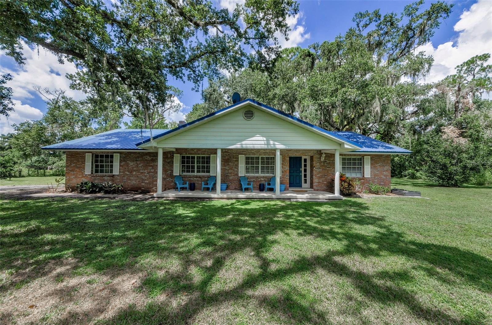 BRING THE HORSES! *NO HOA. NESTLED ON A PRIVATE- SECLUDED (3.24) ACRE FENCED LOT WITH A BARN you will find this charming and spacious 3-bedroom, 2-bath country ranch-style home. As you enter through the front door you are greeted by a wall of flagstone in the foyer. To the left is the combination living/dining room featuring a wood-burning fireplace surrounded by a flagstone wall. The kitchen is equipped with double built-in ovens, solid wood cabinets, and a large island overlooking the family room. The split floor plan offers privacy for all. There is a private hallway leading to the laundry room and the primary suite with two walk-in closets. The primary bathroom offers dual sinks and a jetted tub. On the opposite side of the home are two generously sized bedrooms flanked by a guest bathroom with double sinks and a linen closet. The home also features an oversized side-load one-car garage, rain gutters and a metal roof installed in 2015. Enjoy the outdoor living space on the covered 36'x7' front porch with your morning coffee watching the sunrise or on the 35'x12' screened rear Lanai with a wet bar and a pass-through to the kitchen, perfect for enjoying your favorite beverage while watching a beautiful sunset. No rear neighbors within 20 acres! The property includes an AMAZING 1500 SQUARE FOOT BARN WITH A CENTER ISLE, ELECTRIC, WATER, THREE HORSE STALLS, TACK ROOM, AND TRACTOR GARAGE. * Brand new well, well equipment, and water softener in 2025. This beautiful property is a must-see! NOT in a flood zone and is situated at the end of a paved dead-end road with a winding driveway and towering grandfather oaks that lead you back to the house and the barn. Ready for your personal touches! The location is ideal, just one mile south of I-4. Twenty minutes to downtown Tampa and just a few minutes' drive to Parkesdale farm market, Keel & Curley winery, restaurants, shopping, and Medard Conservation Park, which offers fishing, hiking, boat rentals, and campground. Less than one hour from all the Orlando attractions. Bring your RV, boat, horses, farm animals, and start enjoying the Florida country lifestyle!