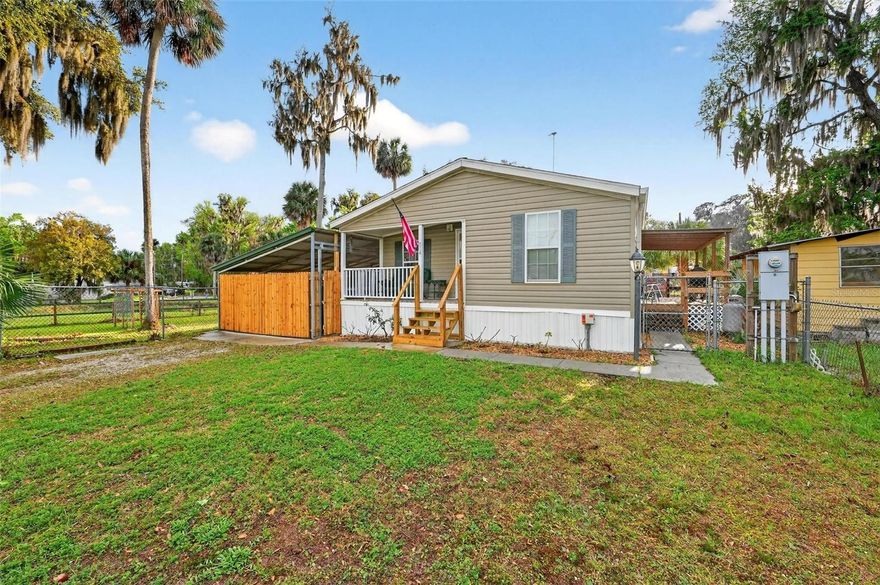 Just a block from the shores of beautiful Lake George, this charming 2015 manufactured home offers the perfect blend of peaceful living and outdoor adventure. Situated on a spacious 100x100 (.31 acre) lot, this 2-bedroom, 2-bathroom home provides a comfortable layout along with inviting outdoor spaces designed for enjoying Florida living year-round. Start your mornings on the welcoming front porch or unwind in the evenings on the side porch while enjoying the quiet surroundings. The property features a large carport for convenient covered parking and a versatile storage shed that has been transformed into a fun outdoor entertainment area complete with a bar—perfect for hosting friends and family. The rear portion of the building still serves as a storage and work area, providing plenty of room for tools, hobbies, or additional storage needs. The property has been thoughtfully arranged with three separately fenced areas, allowing flexibility for pets, gardening, recreation, or additional outdoor projects. Garden lovers will especially appreciate the raised garden beds and the variety of established fruit trees and plants already thriving on the property, including banana trees, blueberries, peach trees, a grapevine arbor, and both orange and lemon trees. An artisan well helps support the outdoor spaces, and the home is equipped with a propane stove and an owned propane tank for added convenience. Water lovers and outdoor enthusiasts will appreciate that the community offers two boat ramps providing easy access to Lake George, part of the St. Johns River system. Lake George is the second largest lake in Florida, stretching approximately 18 miles long and 5 miles wide, and is well known for fishing and crabbing with species including mullet, striped bass, and blue crabs. The lake is fed by the crystal-clear waters of Salt Springs Run. Just minutes away is the popular Salt Springs Recreation Area, open year-round and offering camping, hiking, swimming, and a wide variety of water activities. Its main attraction is a stunning ancient subterranean spring, and the nearby Salt Springs Campground is the largest campground in the Ocala National Forest. Despite the peaceful natural setting, the property is conveniently located approximately 21 miles from Silver Springs, 22 miles from Palatka, 30 miles from Ocala, 43 miles from Daytona Beach, and 45 miles from historic St. Augustine. If you are looking for a home that offers privacy, room to garden, space to entertain, and incredible access to Florida’s natural beauty and waterways, this property is a must see. Schedule your showing today and come experience the relaxed Lake George lifestyle for yourself. While there is not an HOA, there is a $100.00 fee for the community boat ramps and upkeep. All information deemed reliable but must be verified by buyers. All room measurements are approx. and must be also verified by buyers. Please note that while this home has a Fort McCoy mailing address it is located in Silver Springs.