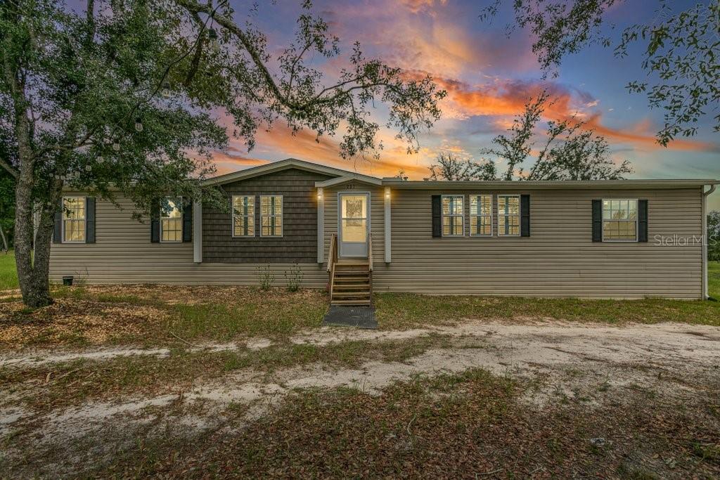 This 17± acre fenced and cross-fenced property offers the ideal setup for a functional, comfortable homestead lifestyle. Located just approximately 0.1 miles off the paved road on a quiet private road, you'll enjoy peaceful seclusion without sacrificing easy access. 10.1+/- acres is located North of Little Orange Creek Road and 7.06+/- acres is located South of Little Orange Creek Road. Buyer may be able to create two individual parcels but would need to confirm with Putnam County Planning and Zoning. Built in 2021, the upgraded manufactured home features quality finishes like sheetrock walls, giving it a more refined and spacious feel than standard models. The 3-bedroom, 2-bathroom split floor plan includes a massive owner's suite with an oversized bathroom, plus multiple living areas including a family room, a separate den, and a spacious dining area—perfect for everyday meals and gatherings. The covered back porch is already wired and plumbed for an outdoor kitchen and TV, making it a great spot for cookouts or relaxing evenings. The land is well-equipped for a working homestead, with separate paddocks for horses, cows, and goats, along with a hog pen and chicken coops. A sturdy pole barn with enclosed sides and a concrete slab provides excellent storage for boats, ATVs, or campers. While the area around the home is cleared and seeded for pasture, portions of the property have been intentionally left wooded to preserve natural habitat and attract wildlife, ideal for hunting or simply enjoying nature. Conveniently located approximately 35 minutes to Palatka, 45 minutes to Gainesville, and just over an hour to Ocala, this property offers the perfect balance of freedom, functionality, and comfort.
