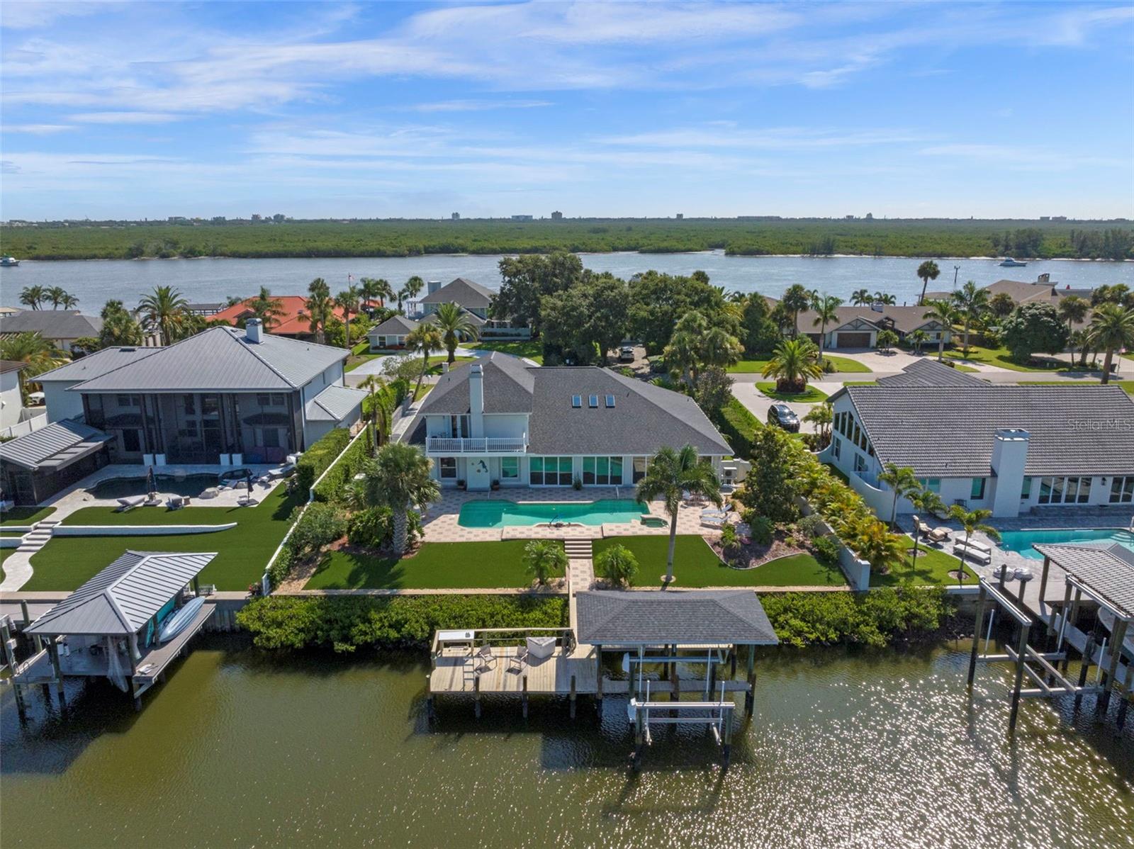 Discover a rare opportunity to own a custom-renovated luxury waterfront home in the exclusive Yacht Club Island Estates—the only gated Intracoastal Waterway community in New Smyrna Beach offering direct deep-water access. Available for the first time in over 25 years, this meticulously maintained coastal estate is a true waterfront treasure, showcasing panoramic views of the Indian River and featuring a private two-slip dock, lifts and station to clean your catch-of-the-day. Nestled within an intimate gated enclave of just 23 homes, this property blends timeless design with modern upgrades in one of Florida’s most coveted fishing and boating communities. The residence offers 4,281 square feet of refined interior space (5,180 total square feet under roof), including 4 bedrooms, 4.5 bathrooms, and flexibility for a secondary primary suite on the main level—ideal for multi-generational living. From the smooth stucco exterior and brick paved driveway to mature landscaping and private courtyard entry, every detail of this home reflects high-end coastal living. Inside, the open-concept layout features 10-foot ceilings and uninterrupted sightlines of the waterway, beginning with a formal living and dining space that flows seamlessly to the spacious family room anchored by a stunning coquina stone gas fireplace with river views to soothe the soul. The remodeled chef’s kitchen serves as the heart of the home, featuring new custom cabinetry, granite countertops, designer lighting, premium appliances, wine fridge, breakfast bar, and a bright breakfast nook. The expansive primary suite offers French doors opening to the sunroom and out to the pool area. Dual walk-in closets, and a spa-inspired ensuite with double vanities, a jetted soaking tub, and a walk-in shower. Upstairs, three additional bedrooms and two bathrooms are complemented by a private balcony overlooking the Intracoastal Waterway. Ideal for entertaining, the 35-foot Florida sunroom features an artist-designed custom bar with a wet sink which opens to an outdoor oasis with new sliding glass doors, a resort-style "volleyball" pool, and a waterfall cascading from the spa. The fully fenced, low-maintenance backyard leads directly to the dock, enhanced by water-to-dock vinyl-wrapped pilings for lasting durability. Additional features include NEW HVAC systems, Anderson Renewal energy-efficient windows, a Generac whole-home generator and central vacuum, interior laundry room, walk-in pantry, and an oversized 3-car garage. This exceptional waterfront property combines luxury, comfort, and functionality in a prime New Smyrna Beach location near the Yacht Club, Historic Canal Street, Flagler Avenue, premier golf courses, and the beautiful sand beaches of the Atlantic Ocean. From sunrise to sunset, this home offers a front-row seat to the natural beauty of coastal living—Don’t miss your opportunity to own this one-of-a-kind waterfront home at 1216 Commodore Drive—schedule your private showing today and experience the very essence of Florida and life on the water.