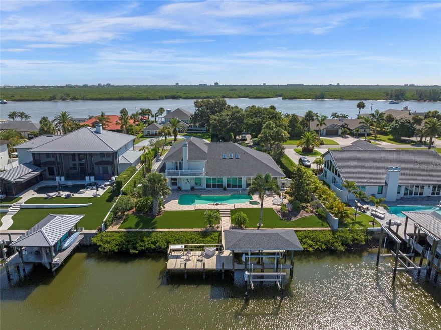 Discover a rare opportunity to own a CUSTOM-RENOVATED luxury WATERFRONT home in the exclusive Yacht Club Island Estates with EASY OWNER FINANCING AVAILABLE AT 4.99% WITH 25% DOWN.—the only gated Intracoastal Waterway community in New Smyrna Beach offering direct deep-water access. Available for the first time in over 25 years, this meticulously maintained coastal estate is a true waterfront treasure, showcasing panoramic views of the Indian River and featuring a private two-slip dock, lifts and station to clean your catch-of-the-day. Nestled within an intimate gated enclave of just 23 homes, this property blends timeless design with modern upgrades in one of Florida’s most coveted fishing and boating communities. The residence offers 4,281 square feet of refined interior space (5,180 total square feet under roof), including 4 bedrooms, 4.5 bathrooms, and flexibility for a secondary primary suite on the main level—ideal for multi-generational living. From the smooth stucco exterior and brick paved driveway to mature landscaping and private courtyard entry, every detail of this home reflects high-end coastal living. Inside, the open-concept layout features 10-foot ceilings and uninterrupted sightlines of the waterway, beginning with a formal living and dining space that flows seamlessly to the spacious family room anchored by a stunning coquina stone gas fireplace with river views to soothe the soul. The remodeled chef’s kitchen serves as the heart of the home, featuring new custom cabinetry, granite countertops, designer lighting, premium appliances, wine fridge, breakfast bar, and a bright breakfast nook. The expansive primary suite offers French doors opening to the sunroom and out to the pool area.  Dual walk-in closets, and a spa-inspired ensuite with double vanities, a jetted soaking tub, and a walk-in shower. Upstairs, three additional bedrooms and two bathrooms are complemented by a private balcony overlooking the Intracoastal Waterway. Ideal for entertaining, the 35-foot Florida sunroom features an artist-designed custom bar with a wet sink which opens to an outdoor oasis with new sliding glass doors, a resort-style "volleyball" pool, and a waterfall cascading from the spa. The fully fenced, low-maintenance backyard leads directly to the dock, enhanced by water-to-dock vinyl-wrapped pilings for lasting durability. Additional features include NEW HVAC systems, Anderson Renewal energy-efficient windows, a Generac whole-home generator and central vacuum, interior laundry room, walk-in pantry, and an oversized 3-car garage. This exceptional waterfront property combines luxury, comfort, and functionality in a prime New Smyrna Beach location near the Yacht Club, Historic Canal Street, Flagler Avenue, premier golf courses, and the beautiful sand beaches of the Atlantic Ocean.  From sunrise to sunset, this home offers a front-row seat to the natural beauty of coastal living—Don’t miss your opportunity to own this one-of-a-kind waterfront home at 1216 Commodore Drive—schedule your private showing today and experience the very essence of Florida and life on the water.
