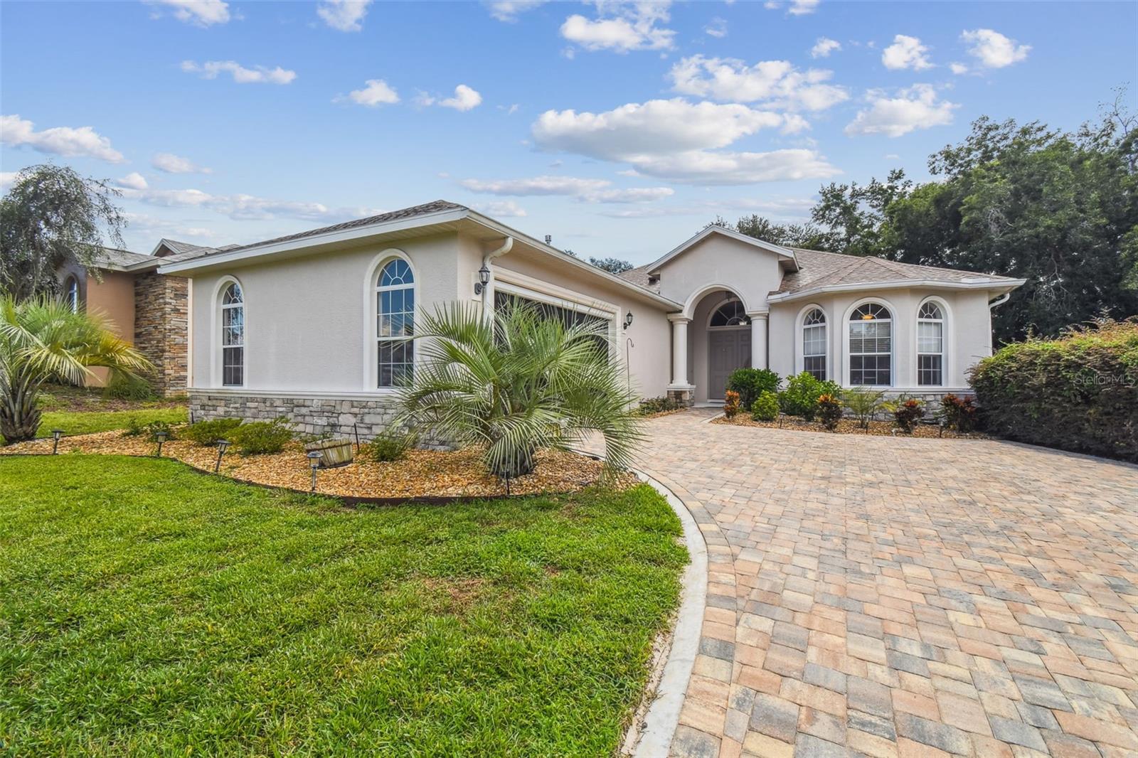 Welcome to your next chapter in one of Florida’s most distinctive 55+ communities—often fondly known as the “Florida Alps” for its rolling terrain reaching elevations up to 200 feet. This 24-hour gated community offers peace of mind along with picturesque surroundings. This thoughtfully maintained 3-bedroom, 2-bath home offers 2,388 square feet of comfort, convenience, and quality craftsmanship. From the moment you arrive, the brand-new pavered driveway sets a polished welcome. Step inside through double front doors and discover luxury vinyl flooring throughout the main living areas, with tile accents in others. The open floor plan includes a spacious dining room, cozy breakfast nook, a dedicated office and a screened in saltwater pool with a fenced in backyard. Added in 2020, the heated pool invites year-round enjoyment and is accessible directly from the oversized primary bedroom. The pool area, fully enclosed by a fenced-in backyard, offers a private and secure outdoor oasis. Whether you're lounging poolside or enjoying an evening under the stars, the defined outdoor living space provides added peace of mind and makes entertaining both easy and enjoyable. French doors lead out from this serene retreat, complete with plantation shutters, a large custom walk-in closet, and an en-suite bathroom featuring double sinks, a soaking tub, and a separate shower. The kitchen offers style and function with white cabinetry, a bar-height counter, and stainless-steel appliances. An electric fireplace warms up the living space, making evening relaxation even more inviting. With a newer roof and air system from 2022, this home provides both beauty and peace of mind. Located just moments from shopping like the nearby Publix Super Market, this location balances tranquility with convenience. And yes, there's even a whole-house water softener—because your water should be as smooth as your new lifestyle. Don’t miss your chance to experience this lifestyle—schedule your showing today before someone else calls it home!