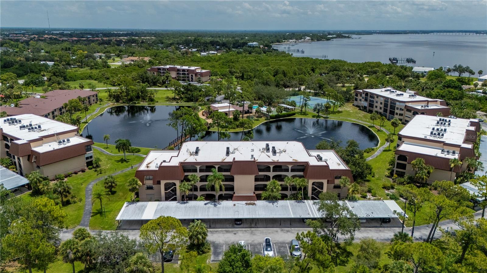A peaceful serenity awaits you with this ground-floor, 2 bedroom, 2 bath, lakefront condominium in Rolls Landing, one of Charlotte County’s most desired communities. As you pass through the security gate into this welcoming enclave, the pristine grounds and inviting atmosphere immediately set the tone for the Florida lifestyle you’ve been dreaming of. Pulling into your assigned covered parking space, you’ll appreciate not only its convenience, especially on rainy days with an armful of groceries-but also the additional storage closet located just in front, perfect for stowing your beach chairs, fishing gear, or holiday decorations. Step inside to discover new carpet throughout, adding warmth and comfort to the open, light-filled layout. You’ll be instantly drawn to the breathtaking lakefront vistas, the hallmark of this exceptional community. The electric hurricane roll-down shutters provide both security and peace of mind with just the touch of a button.The primary suite offers ample space for a home office or creative nook, complete with an en suite bath for privacy and comfort. Plank tile flooring in the dining area flows into the updated kitchen, featuring an abundance of raised panel cabinetry, a tray ceiling, and recessed lighting-an inviting hub for gatherings. Enjoy an early morning walk or sunset stroll along the meandering lakefront path. Take part in social events at the poolside community center, challenge friends to pickleball, tennis, or shuffleboard, or launch your kayak for a day exploring the Peace River. Boat owners will appreciate the community dock (assessments paid and in progress of being rebuilt), and everyone will savor the stunning harbor sunsets and balmy breezes. All this, just minutes from Punta Gorda’s historic waterfront, Fisherman’s Village, and the new dining options at Sunseeker Resort. This is more than a home-it’s your gateway to the very best of Florida living.