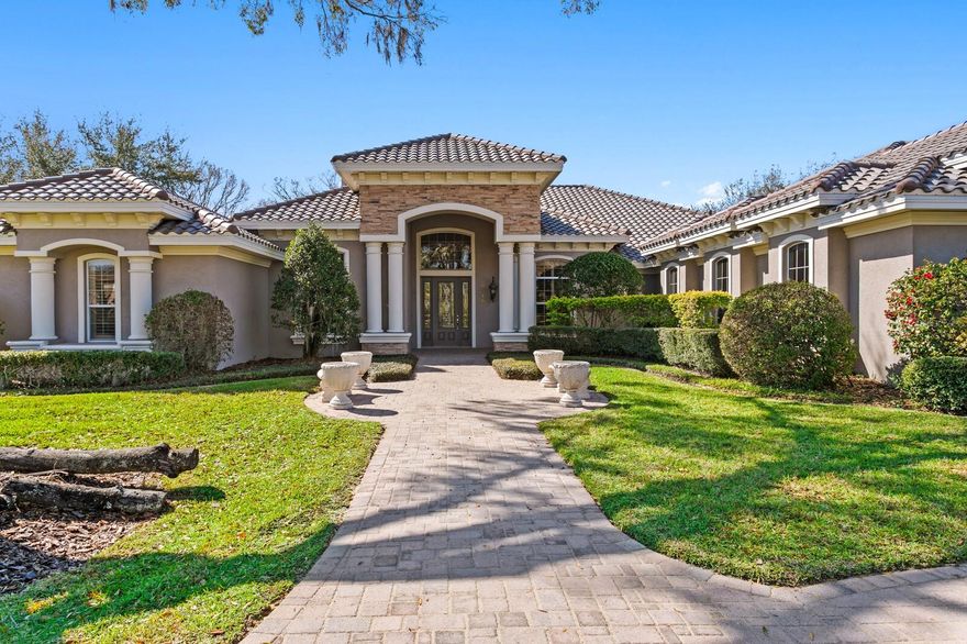 Set on a pristine 1-acre homesite within the gated enclave of Northbridge at Lake Pretty, this fully updated estate delivers architectural presence, refined finishes, and exceptional privacy in one of Odessa’s most sought-after communities. This expansive residence offers over 5,300 square feet of living space, all thoughtfully designed on one level. Single-story estates of this scale are exceptionally rare, delivering seamless flow, ease of living, and architectural presence without stairs. A sweeping brick paver circular drive leads to a stately columned portico, creating a striking first impression. Inside, a dramatic two-story foyer with soaring 20-foot ceilings and statement lighting sets the tone for the scale and sophistication carried throughout the home. The private office is richly detailed with crown molding, wainscoting, and chair rail, offering an elegant workspace. Opposite, the formal dining room features a tray ceiling with uplighting and a designer Restoration Hardware fixture, ideal for elevated entertaining. The formal living room is centered beneath a sculptural globe chandelier and framed by quad French doors that open to the outdoor living spaces. Hardwood floors flow throughout the main living areas, complemented by plantation shutters and extensive crown molding. At the heart of the home, the expansive gourmet kitchen is designed for both everyday living and entertaining. Two oversized islands provide generous prep and gathering space, one with a breakfast bar and the other with a vegetable sink. Custom 42-inch wood cabinetry, granite countertops and backsplash, a walk-in pantry, wine refrigeration, induction cooktop, with propane service already in place for those who prefer a gas range. Premium Dacor stainless appliances complete the space. The adjacent great room features a gas fireplace wrapped in floor-to-ceiling granite, creating a cohesive and dramatic focal point. The owner’s retreat is privately positioned and generously scaled, offering dual walk-in closets and a versatile bonus space ideal for a fitness room, dressing room, or secure storage. The spa-inspired primary bath has been completely reimagined with a freestanding soaking tub, an expansive walk-in shower, dual vanities with full-height mirrors, and designer lighting. All bathrooms throughout the residence have been fully renovated with refined, modern finishes, ensuring a cohesive, move-in-ready experience across every suite and guest space. Three additional bedrooms each include walk-in closets and private ensuite baths, delivering comfort and privacy for family and guests. A massive bonus room provides endless flexibility, currently configured as an entertainment lounge with multiple mounted televisions and direct French door access to the outdoor living areas. Step outside to a private resort-style setting featuring a brick paver pool deck, covered lanai, outdoor kitchen with grill and vent hood, sparkling pool with spillover spa, and mature landscaping that enhances privacy. Significant recent upgrades include a brand-new tile roof, adding both value and long-term peace of mind. The oversized four-car garage offers ample space for vehicles, storage, or a home gym. Residents of Northbridge at Lake Pretty enjoy exclusive lake access for kayaking, paddle boarding, and canoeing, all within a secure gated setting just minutes from top-rated schools, shopping, and dining. This is estate living without compromise.