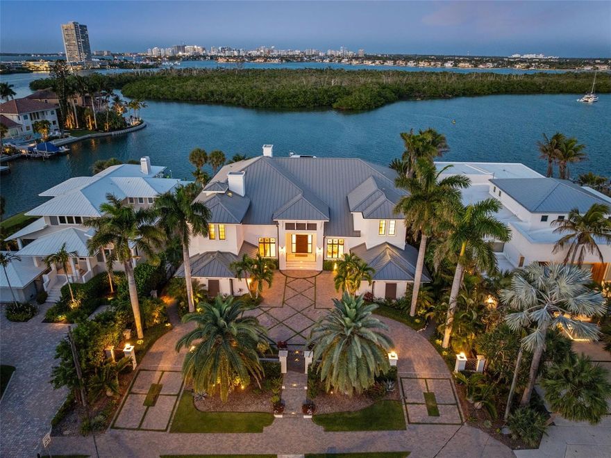 A stunning, fully reimagined coastal residence where elevated design meets modern functionality. Rebuilt to the studs and thoughtfully curated throughout, this expansive home showcases exceptional craftsmanship, custom finishes, and seamless indoor-outdoor living—all in a premier location just moments from the pristine Gulf beaches and the world-class shopping and dining of St. Armands Circle. Inside, light-filled interiors feature level 5 smooth walls, engineered hardwood floors, custom coffered ceilings, and extensive crown molding. The main living areas are anchored by two striking gas fireplaces with imported designer tile, while bifold and accordion glass doors open to expansive terraces, creating effortless flow for entertaining. The chef’s kitchen is a true showpiece with leathered granite countertops, a large island with bar seating, and top-tier appliances including a Wolf 6-burner gas range, Sub-Zero refrigerator, Miele built-in coffee system, dual dishwashers, and JennAir convection/steam oven. Custom cabinetry and a walk-in pantry complete the space. Designed for both relaxation and entertaining, the home features a private movie theater with Sony projection, B&W surround sound, and Octane seating, along with a game room, multiple office spaces, wet bar, and a 72-bottle wine display. The primary suite offers a private retreat with terrace access, tray ceiling, and a spa-like bath with marble floors, soaking tub, dual vanities, and a walk-in shower. Upstairs bedrooms feature ensuite or Jack-and-Jill baths. Smart features include electric shades, Sonos audio & Lutron Homeworks, central vacuum, and elevator access. Outdoor living shines with a resort-style saltwater pool and spa, waterfall, sun shelf, and integrated audio. The main terrace includes a gas grill, beverage fridge, beer tap, and firepit, with additional upper-level terraces & spectacular water views from every level. Boaters will appreciate the private dock with a 10,000 lb lift, dual jet ski lifts, and the rare ability to accommodate a 64-foot yacht. Additional highlights include impact windows and doors, Tesla charger, epoxy garage floors, and tankless water heaters. This exceptional property blends luxury, technology, and coastal living just moments from the best of Sarasota.