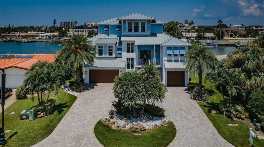 WELL-BUILT WITH AN EXCITING CUSTOM ARCHITECTURAL DESIGN, THIS GORGEOUS COASTAL CONTEMPORARY WATERFRONT RESIDENCE FEATURES BEAUTIFUL WATER VIEWS AND LUXURIOUS FINISHES THROUGHOUT! Beyond its deep circular paver driveway and tall covered entry, discover a home with resplendent wood-finish details, driftwood-style porcelain floors and 11ft-high ceilings. Welcome to an alluring great room plan with sweeping view of the waterfront. The grand living room offers a modern gas fireplace with tumbled marble façade, shiplap accents, built-ins and entertainment wall. A posh culinary delight, the elegant gourmet kitchen boasts Wolf/Subzero appliances, gas cooking, fine quartz counters, coastal white shaker-style cabinetry and a large island dining bar & prep center. A sizable waterfront dining area includes separate built-in lounging/storage. The attractive laundry room contains rich cabinetry/counters, matching the kitchen. Separate built-in work desk is complemented by a lovely ½ bath with beaded-board wainscoting. Awaken to wonderful water views from your private owner’s suite with shiplap accent wall, oversized closet system and private access to covered waterfront balcony. Sumptuous owner’s bath provides lavish dual vanities and a dazzling walk-in, multi-head, glass rainshower enclosure with superior tilework. Step out to the 35ft-wide covered balcony overlooking the water – a great place to dine, relax and entertain. Upstairs, you’ll find a terrific open family room area that connects 3 additional bedrooms, all oversized and all overlooking the waterfront. 2nd bedroom is en suite with a luxury full bath and walk-in closet. 3rd and 4th guest bedrooms enjoy a graceful guest bath with dual vanities. All 3 upper-level bedrooms have private access to a 200 sqft covered balcony with fabulous views of the open water. Lower level has generous garage parking and an 890sqft multi-purpose area with porcelain tile floors. Lower level opens to a 270sqft covered area overlooking the pool/waterfront, a space ideal for covered lounging/poolside dining. A superb travertine paver deck surrounds the striking pool/spa with waterfall and sun shelf lounging area. Updated seawall and composite dock support 2 jetski lifts and an impressive 25,000 lb boatlift – from here, you’ll be in the open waterway in 20 seconds. 3-stop elevator, natural gas, splendid window treatments (some automated), and much more. A fantastic value in a premier boating and beach community! Dimensions are estimates, buyer to confirm.