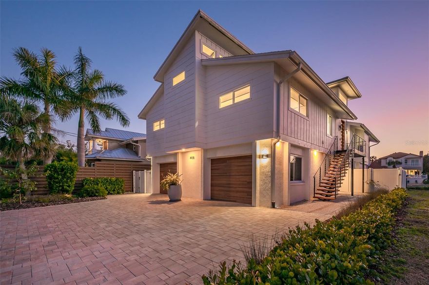 Experience the pinnacle of waterfront luxury on Siesta Key’s prestigious Grand Canal. This meticulously reimagined residence at 4938 Commonwealth Drive offers a rare blend of modern sophistication, structural integrity, and complete peace of mind. Extensively transformed both structurally and aesthetically, the home welcomes you into an expansive open-concept design filled with natural light. The newly expanded kitchen serves as the heart of the home, offering abundant cabinetry and storage, a double oven, generous pantry storage, striking custom beam detail, an open breakfast bar, and direct access to the wraparound decking—creating seamless indoor-outdoor living and effortless entertaining. A stylish powder room has also been thoughtfully added. New hurricane-impact windows and sliding glass doors frame the interiors, while designer flooring flows beautifully throughout both levels. Major system upgrades elevate the home’s value and efficiency, including a brand-new roof and a comprehensive solar power system with battery storage. A fresh, contemporary interior palette enhances the clean architectural lines and airy coastal feel. The lower level adds over 1,300 square feet of legal non-conforming living space with its own private entry, garage access, and elevator connection to the main living areas, leading directly to the pool deck. Redesigned for modern functionality, this space features a spacious family entertainment area, custom bar, and an additional guest suite with a walk-in closet and full bath—ideal for extended family, guests, or a private retreat. Outdoor living is equally impressive. The private backyard sanctuary showcases a heated pool and spa with a new heater and filtration system, sleek updated decking, professional landscaping, and premium artificial turf for effortless maintenance. For the boating enthusiast, the deep-water dock and boat lift provide direct access to the Intracoastal Waterway and open waters of Sarasota Bay, delivering the ultimate waterfront lifestyle.