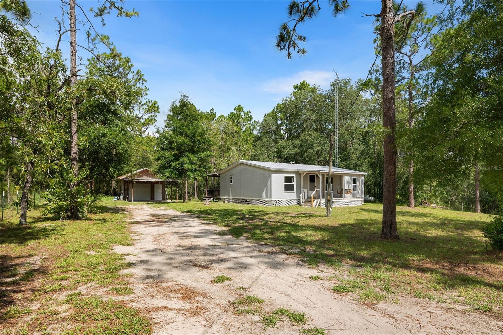 One or more photo(s) has been virtually staged. Tucked into a secluded country setting on two lots totaling almost three acres outside of Williston, this three bedroom, two bathroom home offers a bright and spacious floor plan with fresh interior paint and new carpet with tile flooring. The kitchen offers plenty of cabinetry for storage with nice countertops and appliances. The primary suite is very spacious with an attached bathroom and large closet. Two roomy guest bedrooms share a hall bathroom. Recent updates include a metal roof and windows. Outside the property, you have a large deck overlooking the backyard with large trees, palms, and a variety of plants, offering peaceful privacy. A detached carport and workshop with electric offers more storage and many possibilities. A short drive gives access to recreational opportunities at the Gulf, Rainbow and Suwannee Rivers, Cedar Key, Devil's Den and Blue Grotto, as well as shopping, dining and hospitals in Ocala and Gainesville. Call today for a private tour!