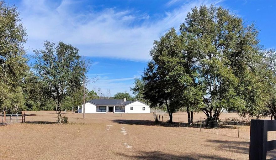 Set on 10.14 fully fenced acres, this 5,100 sq. ft. concrete block home blends modern elegance with the freedom of true country living. Thoughtfully updated and designed for both everyday comfort and memorable entertaining, this 4-bedroom, 3-bath residence offers space, privacy, and versatility in a peaceful, oak-studded setting. The heart of the home is a chef’s kitchen featuring a gas range, prep sink, full sink, abundant counter space, and an oversized walk-in pantry with a second refrigerator—ideal for hosting gatherings large or small. A butler’s pantry/laundry room with sink adds functionality and convenience. Multiple living areas include a media/movie room, a welcoming fireplace, and two dedicated office spaces, providing flexibility for work, relaxation, or creative pursuits. The layout flows effortlessly, balancing open entertaining areas with private retreats throughout. The primary bedroom wing is a true sanctuary, offering an oversized, light-filled bedroom and a spa-inspired bath with a dual-head shower, classic clawfoot soaking tub, private water closet, and space for a personal pampering or relaxation area. Each bathroom throughout the home continues the spa-like feel with oversized showers, clawfoot tubs, and private water closets, offering comfort and privacy for both residents and guests. Extensive updates add confidence and efficiency, including a new roof (2024), water heaters installed in 2023, and two 5-ton HVAC systems (2023 & 2025). Major interior improvements completed in 2023 include all-house electrical (including panels), insulation, drywall, and updated tub and shower plumbing. The attic features open-cell spray foam insulation, and the full exterior stucco was completed in 2023, enhancing durability and curb appeal. A water treatment system installed in 2024 adds another layer of modern convenience. Both the front and back covered porches provide inviting spaces to enjoy cool breezes, sweeping pasture views, and the surrounding natural beauty. Outdoors, the property offers multiple fenced pastures, mature oak trees, and room for horses or other animals, delivering true space to breathe, roam, and enjoy country living—without sacrificing modern comfort. This is more than a home—it’s a thoughtfully updated estate offering space, quality, and a lifestyle of comfort, privacy, and understated sophistication.