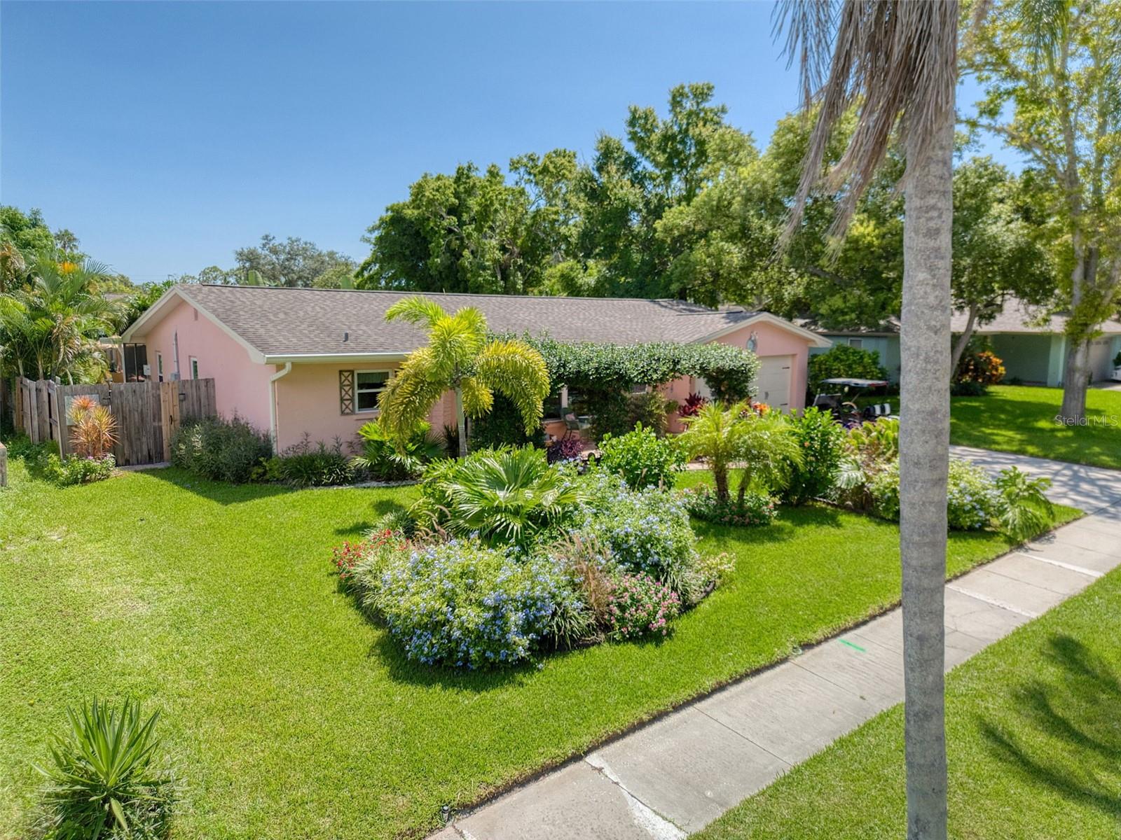 This tres chic 2 bedroom, 2 bath pool home sits gracefully on a beautifully landscaped oversized lot, NOT A FLOOD ZONE in the desirable Ranchwood Estates neighborhood in the delightful Dunedin golf cart area. Jump into your golf cart and venture downtown for dinner, or one of the many festivals or farmers markets. This charming home is tastefully renovated and boasts a living room, formal dining room and a large Florida room, 2 generous sized bedrooms both with ensuite bathrooms; and a spacious kitchen with exquisite granite countertops, 42" soft close white cabinetry and newer stainless steel appliances. The primary bedroom is split from the other bedroom and is a bright and spacious retreat with an ensuite bathroom. The primary bathroom features a farmhouse sink with a marble countertop, and a generous shower/bath combo featuring a new cast iron Kohler tub. There is also a bathroom ensuite off the oversized 2nd bedroom that is tastefully renovated and features a beautiful large walk in shower. The huge Oasis backyard is awesome! It is so beautiful outside with stylish pavers and many native flowers and plants that attract birds and butterflies. The jewel of this magnificent backyard is a heated salt water pool (2020). The backyard is accessed from the light and bright Florida room, opening up on to a large paved patio with a gazebo for a seamless blend of indoor/outdoor entertainment living. The spacious yard is fenced for privacy and pool safety. This home is move in ready with tasteful touches such as; neutral color tones, newer fans, modern light fixtures, porcelain wood look tile floors throughout this impeccably clean and welcoming home. This home also features newer rain gutters, hurricane impact windows (2019), newer flat roof (2022), main roof (2014), a/c (2020) and a newer hurricane garage door. There is plenty of natural light and room to grow in this well laid out open floor plan. This layout allows the ability to covert the formal dining room into an office or 3rd bedroom. Couple this with excellent schools and close to shops, airports, beaches and all that fabulous downtown Dunedin has to offer and you have the quintessential Florida lifestyle home.