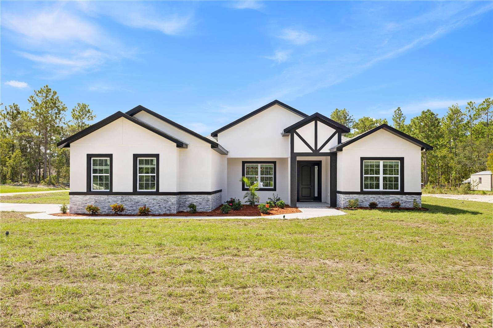 Beautiful new construction on a spacious 1.07 ACRE CORNER LOT with a PRIVATE IN-LAW SUITE featuring a separate entrance, included in the 4 bedrooms and 3 bathrooms. The open layout showcases a modern kitchen with a quartz waterfall island accented by wood slats, sleek cabinetry, a elegant chandelier, and dark contemporary fixtures. The spacious primary suite offers a walk-in closet and spa-like bath. Outdoor living shines with a covered lanai and SUMMER KITCHEN, perfect for entertaining. Additional highlights include a 2-car garage, 2,226 sq. ft. of stylish living space, smart key system for enhanced security, and the peace of mind that comes with a 2-10 Home Buyers Warranty. Don’t miss out—schedule a showing today!