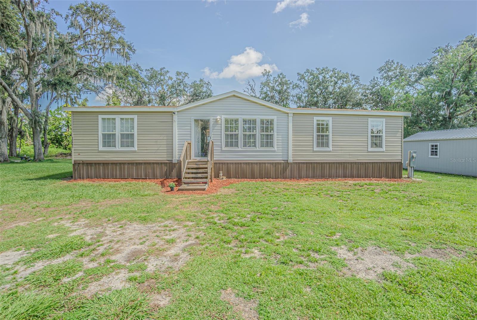 This spacious 4-bedroom, 2-bath double wide manufactured home sits on just over an acre with no HOA or CDD—offering the perfect blend of country charm and modern convenience. Step inside to a bright, open floor plan featuring a large kitchen island, abundant cabinet space, and a walk-in pantry for all your storage needs. The split-bedroom layout provides added privacy, while the generous living and dining areas are ideal for relaxing or entertaining. Located on a quiet street, yet just minutes from shopping, dining, and major highways—this property is perfect for those seeking space, comfort, and flexibility. Don’t miss your chance to make this Wesley Chapel gem your own!