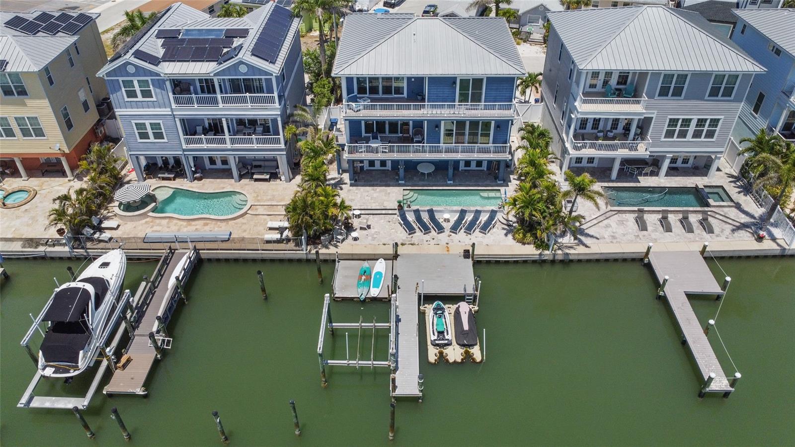 Newer Built Custom Waterfront Madeira Beach Luxury Paradise. 4 Bedroom/3.5 bathroom + an office and fully permitted and remodeled apartment style suite on the 1st floor (perfect for extended family and/or guests). With 54 feet of private waterfront, 12,000 lb boat lift, two jet ski water ramps, and panoramic Intercoastal and Gulf of America views, this masterpiece offers coastal luxury in a very private neighborhood with fantastic neighbors and NO HOA! The open floorplan is adorned with crown molding, bamboo and tile flooring, solid wood cabinetry, stone countertops and split bedroom design. Enjoy the view from virtually every room through the floor to ceiling windows creating a welcoming, airy atmosphere. This home features a state-of-the-art security system, two new A/C units (installed August 2024) with a transferrable warranty, saltwater pool (with new pump installed April 2025) surrounded by a private fenced yard, 54-foot seawall offering an unforgettable view of picturesque Snug Harbor, Gulf of America, and the intercoastal enjoyed from every floor if this home from inside and out. Multiple balconies and decks to take it all in. Spacious two car split garages offer secured parking. Located in Gulf Shores Harbor just off Gulf Blvd near the Church by the Sea and minutes from all of Pinellas County Beaches. This neighborhood offers a public beach access just across the street to the sugar white sands of Madeira Beach, is pet-friendly, and no HOA. Coastal luxury awaits! Step right inside and you will never want to leave this true Florida coastal lifestyle!